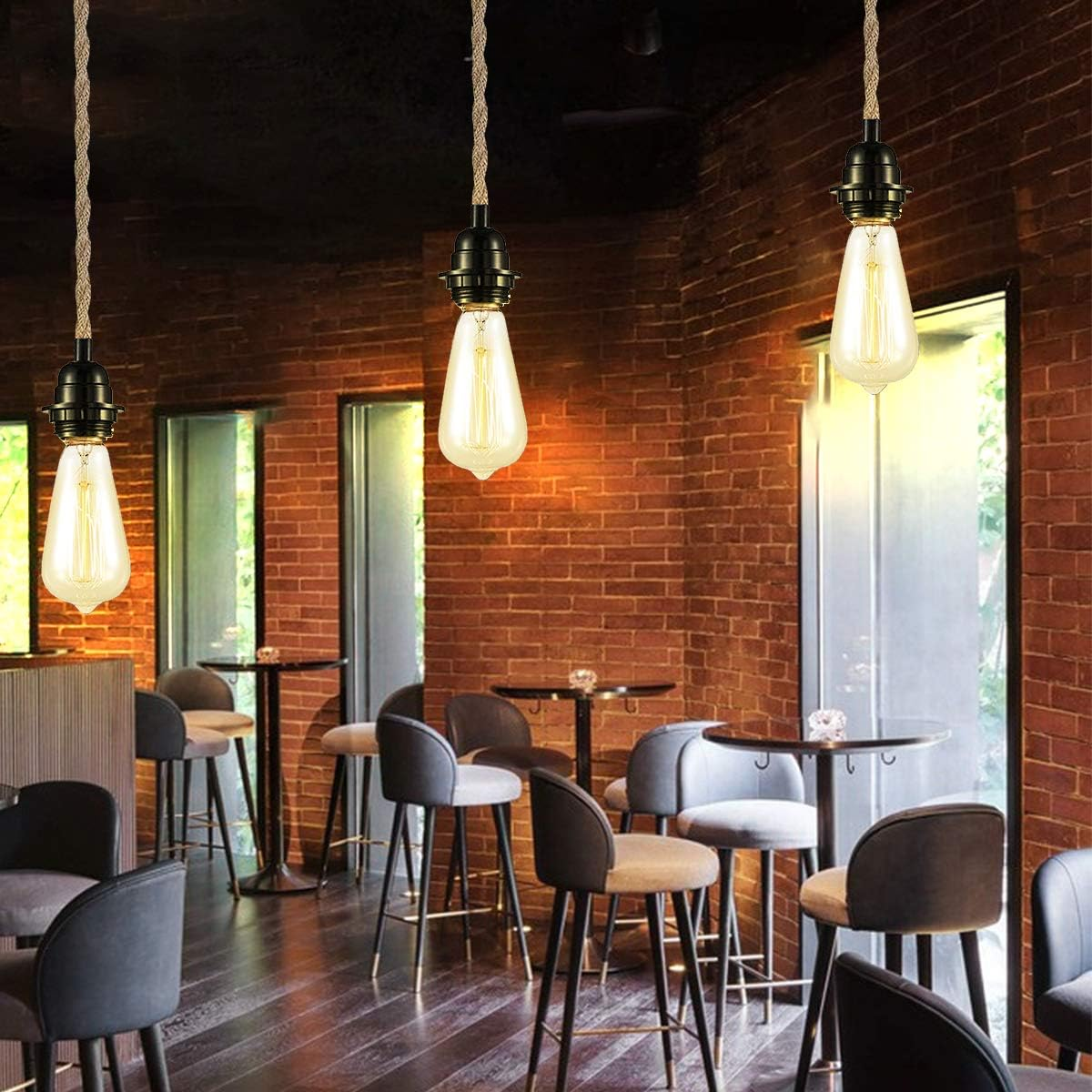 Innenraum einer Bar mit Hängelampen, Backsteinmauern, kleinen Tischen und Stühlen. Die Beleuchtung sorgt für ein warmes Ambiente.