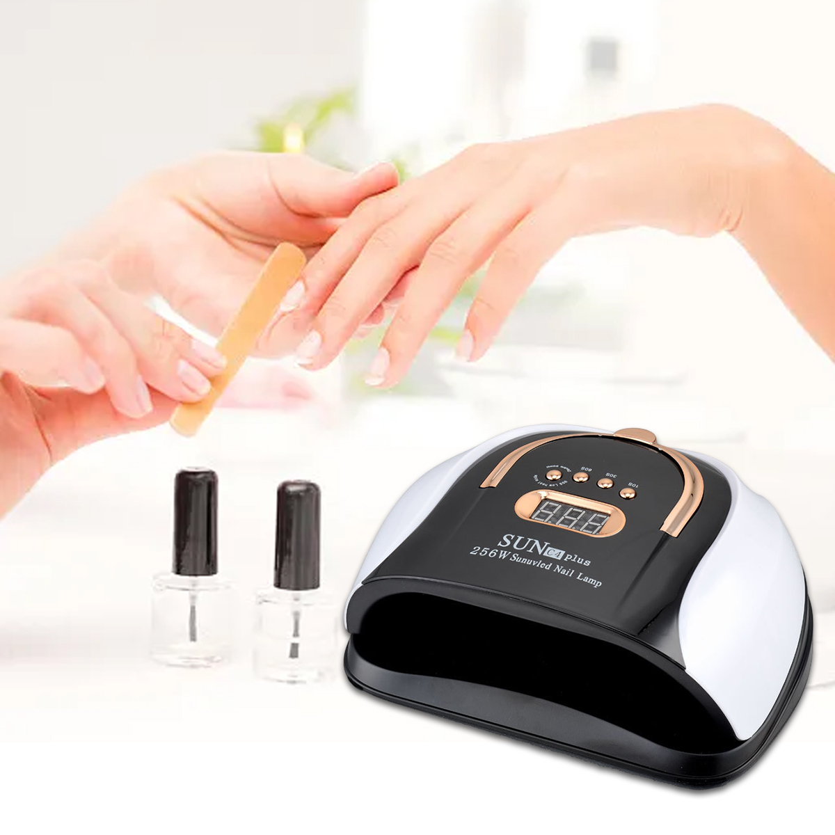Eine Person feilt Nägel. Nagellackflaschen und eine UV-Nagellampe befinden sich im Vordergrund. Die Lampe ist schwarz, weiß und gold.