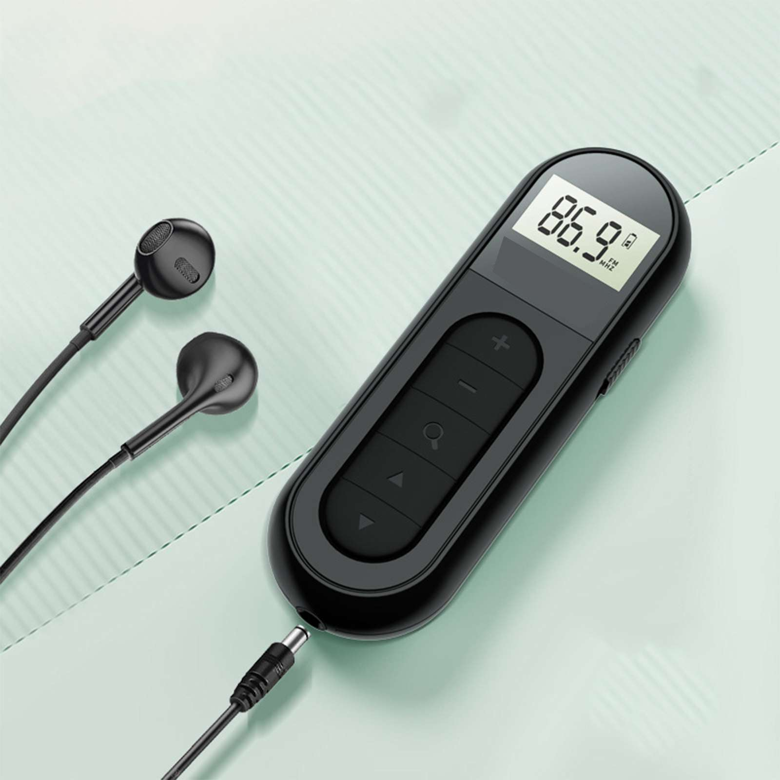 Schwarzes Radio mit Display, das 86,9 MHz anzeigt, mit angeschlossenen Ohrhörern und einem Stromkabel, auf hellgrüner Oberfläche.