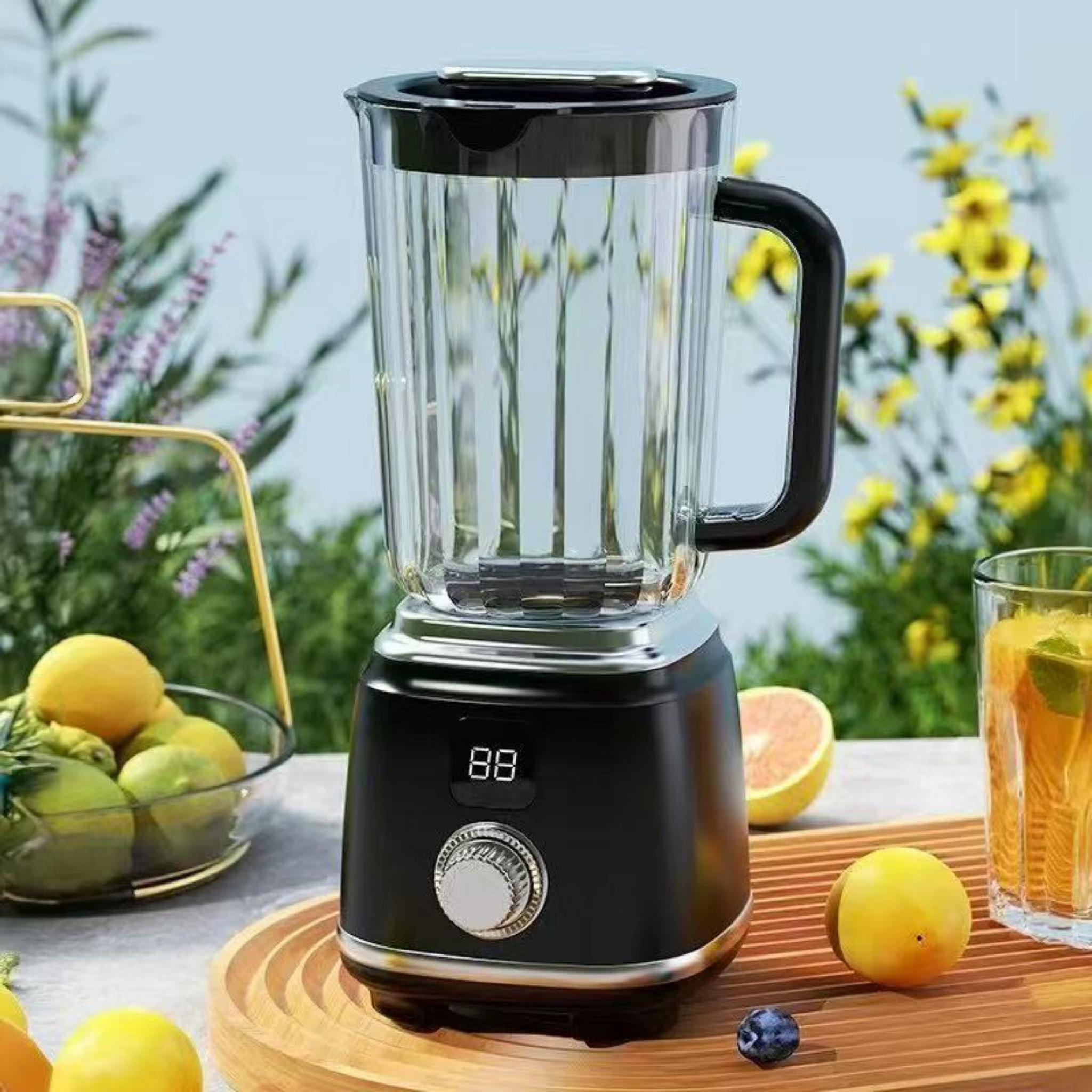 Ein schwarzer Mixer auf einem Holztablett, mit Zitronen, einem Glas Saft und einer Schüssel mit Früchten. Blumen im Hintergrund.