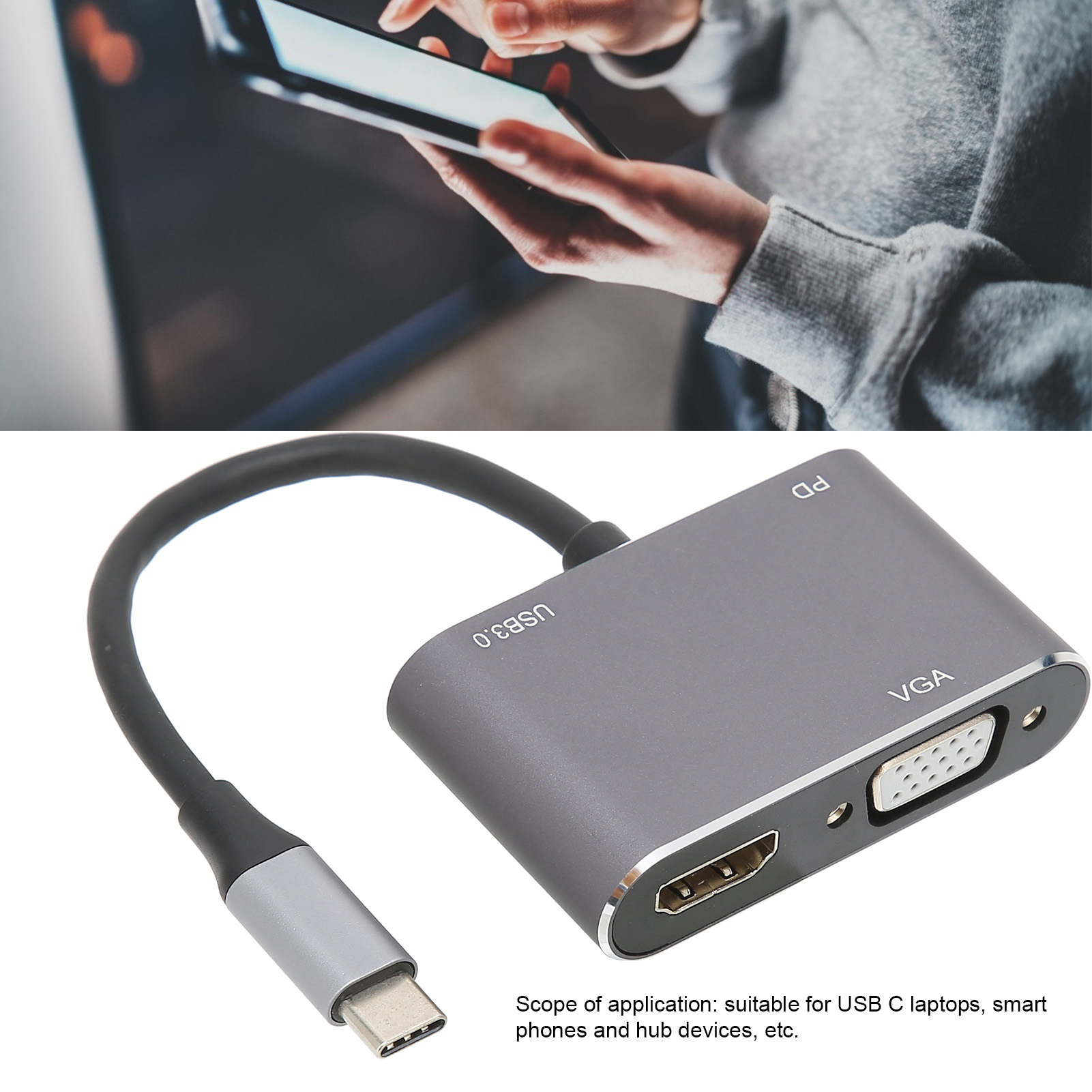 Ein grauer USB-C-Adapter mit HDMI- und VGA-Anschlüssen. Im Hintergrund bedient eine Person ein Tablet.