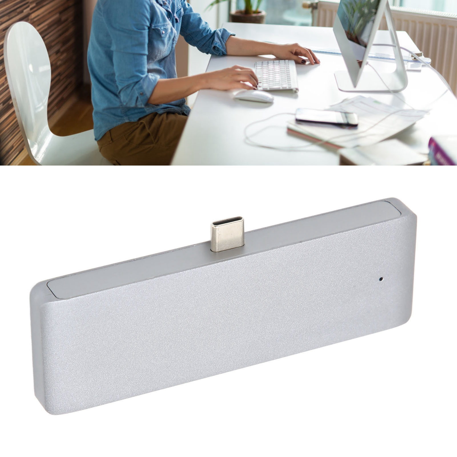 Eine Person benutzt einen Computer. Darunter ist ein silberner USB-C-Hub.