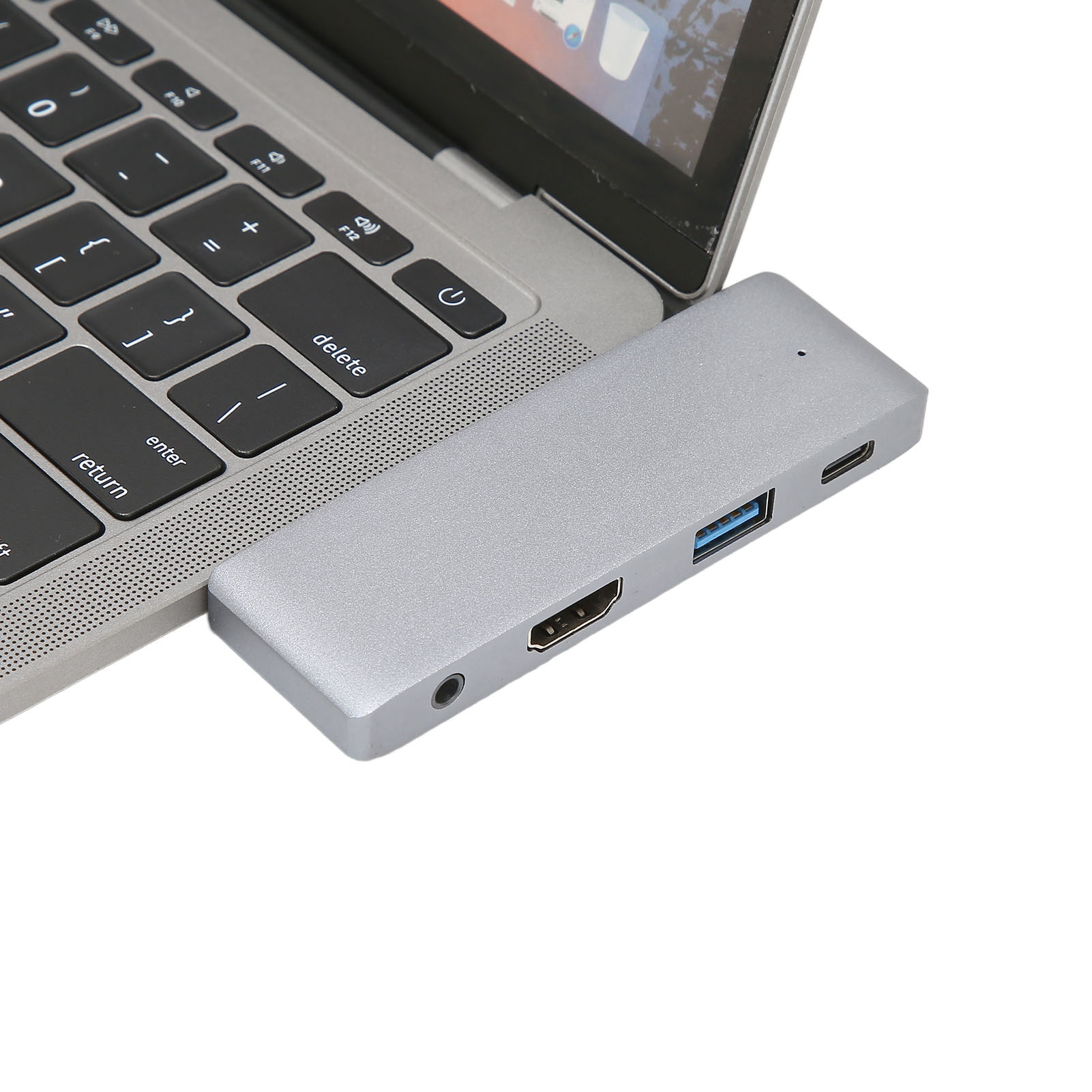 Ein Laptop mit einem silbernen Hub, der Anschlüsse zeigt. Die Laptop-Tastatur ist sichtbar. Der Hintergrund ist weiß.