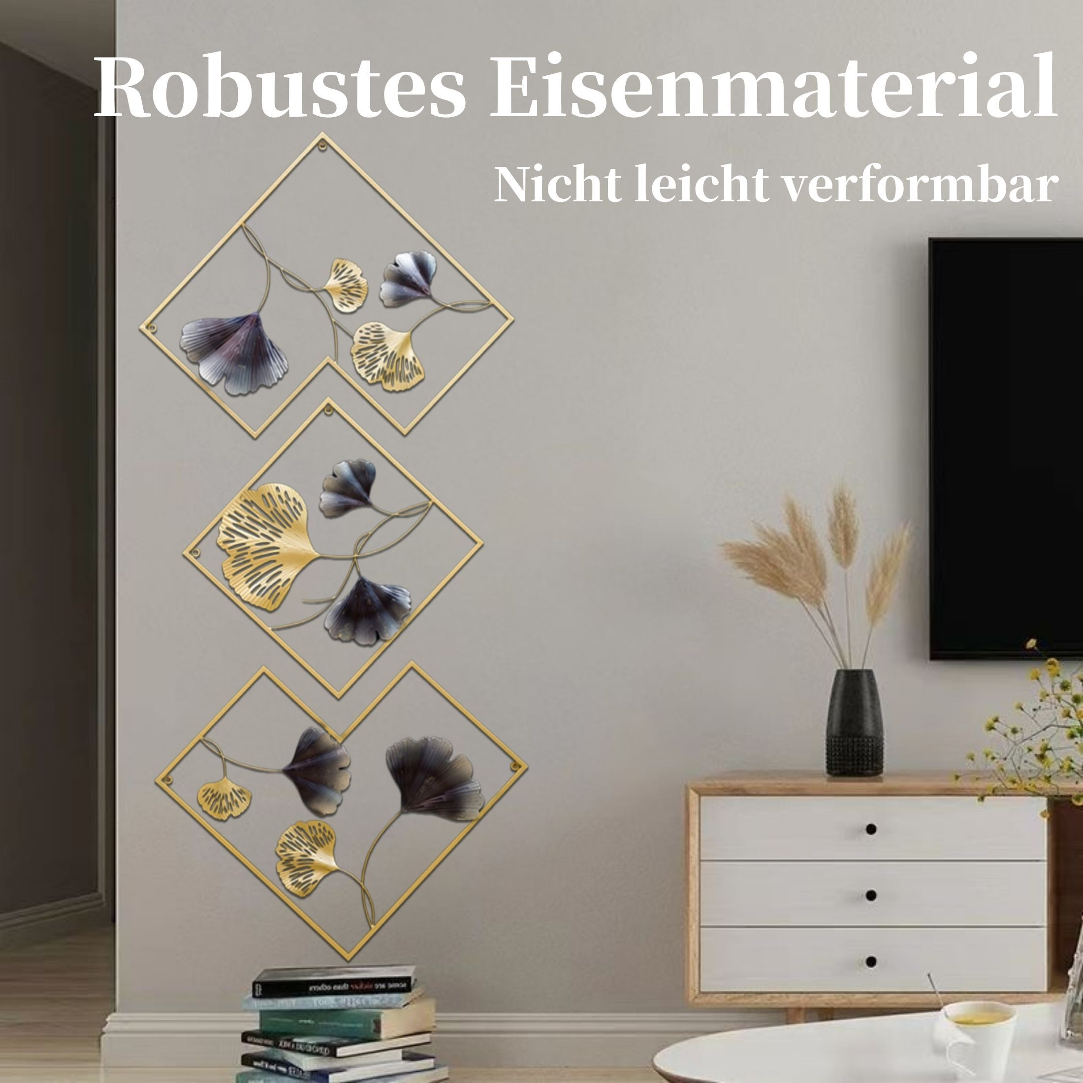 Wandkunst mit goldenen Rahmen und Metallblättern. Eine Vase mit Weizen und ein Schrank sind vorhanden. Texte stehen oben.
