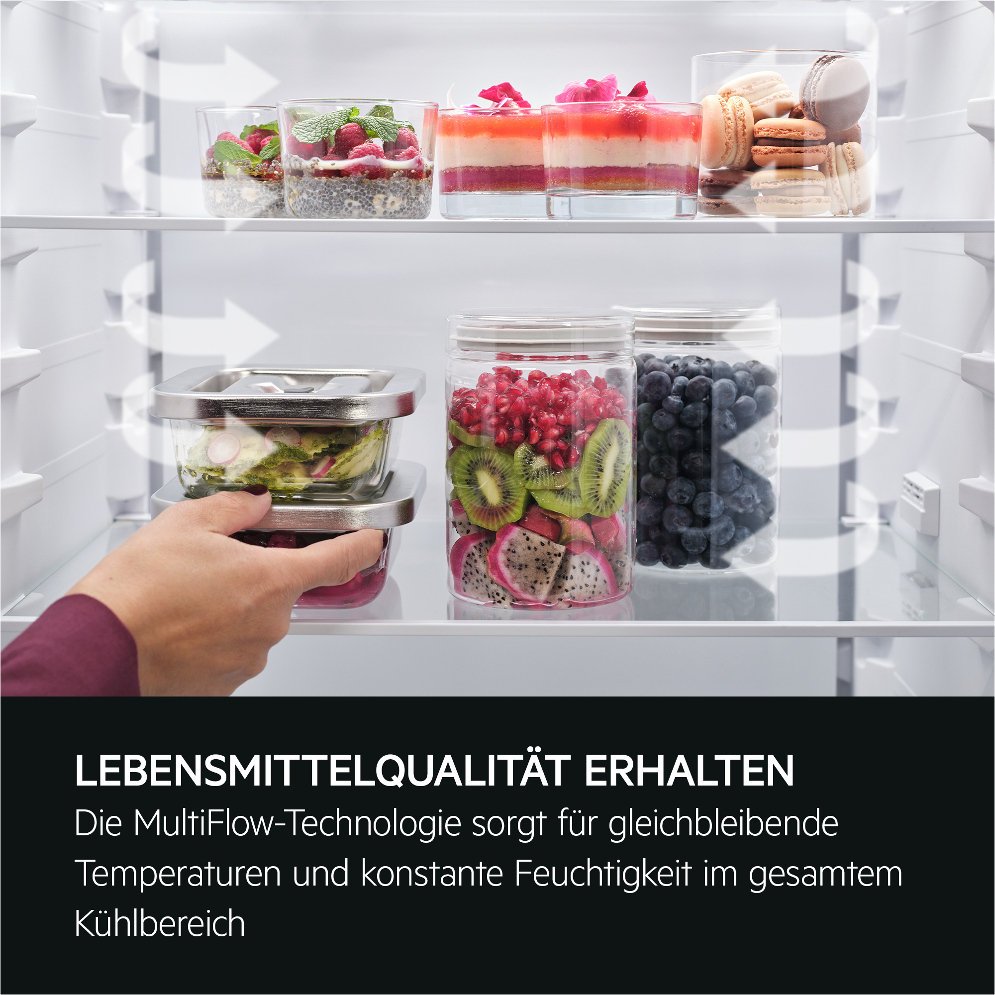 Ein Kühlschrank-Innenraum ist mit Glasbehältern mit Desserts und Früchten gefüllt. Eine Hand greift nach den Glasbehältern.