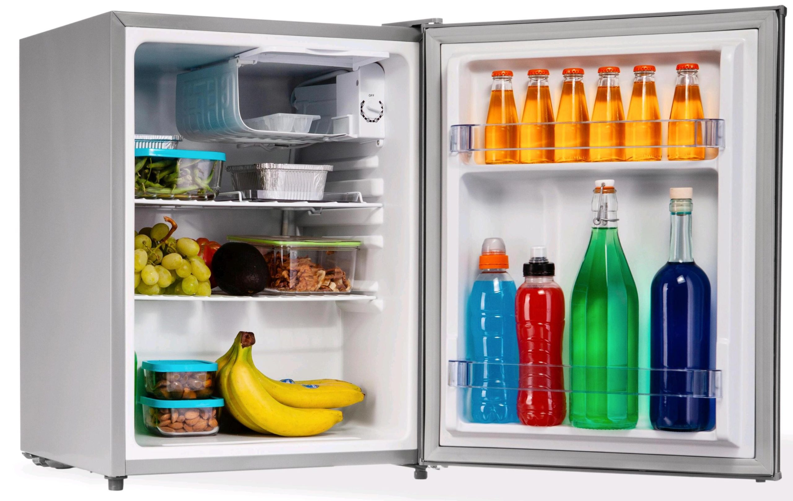Un piccolo frigorifero è aperto, che mostra cibo e bevande come frutta, bottiglie e contenitori.