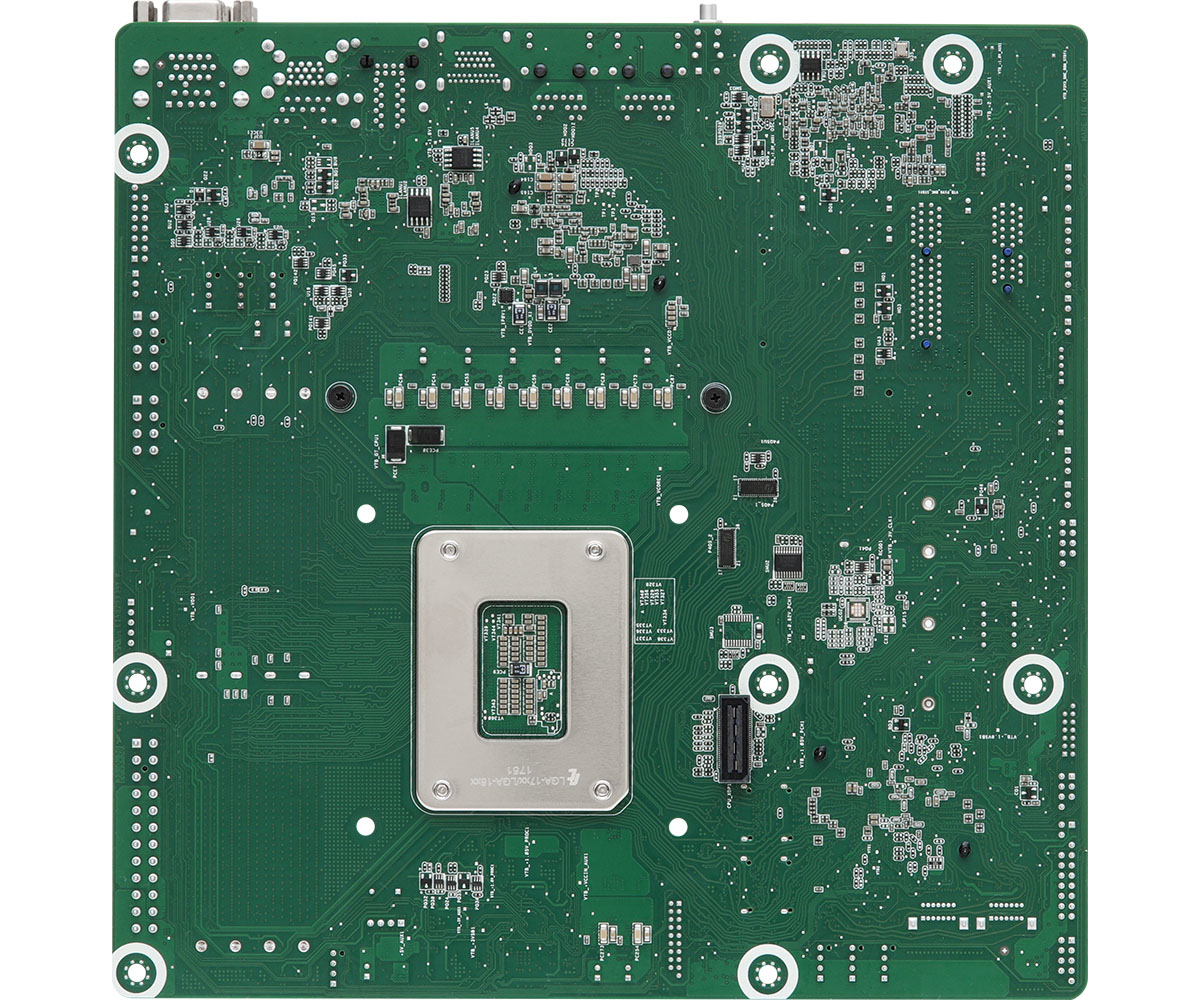 Un circuito stampato verde con numerosi componenti elettronici, tra cui chip, connettori e un socket centrale per il processore. Sono visibili fori di montaggio bianchi.