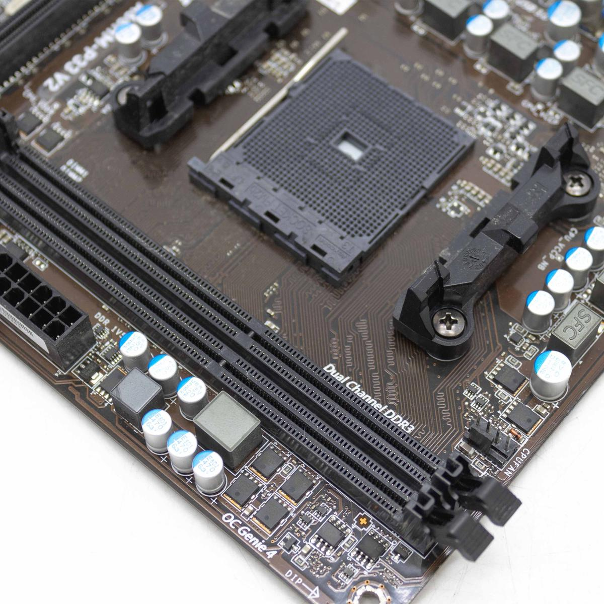 Una scheda madre di computer marrone con componenti neri, tra cui slot, un socket CPU e condensatori, su sfondo bianco.