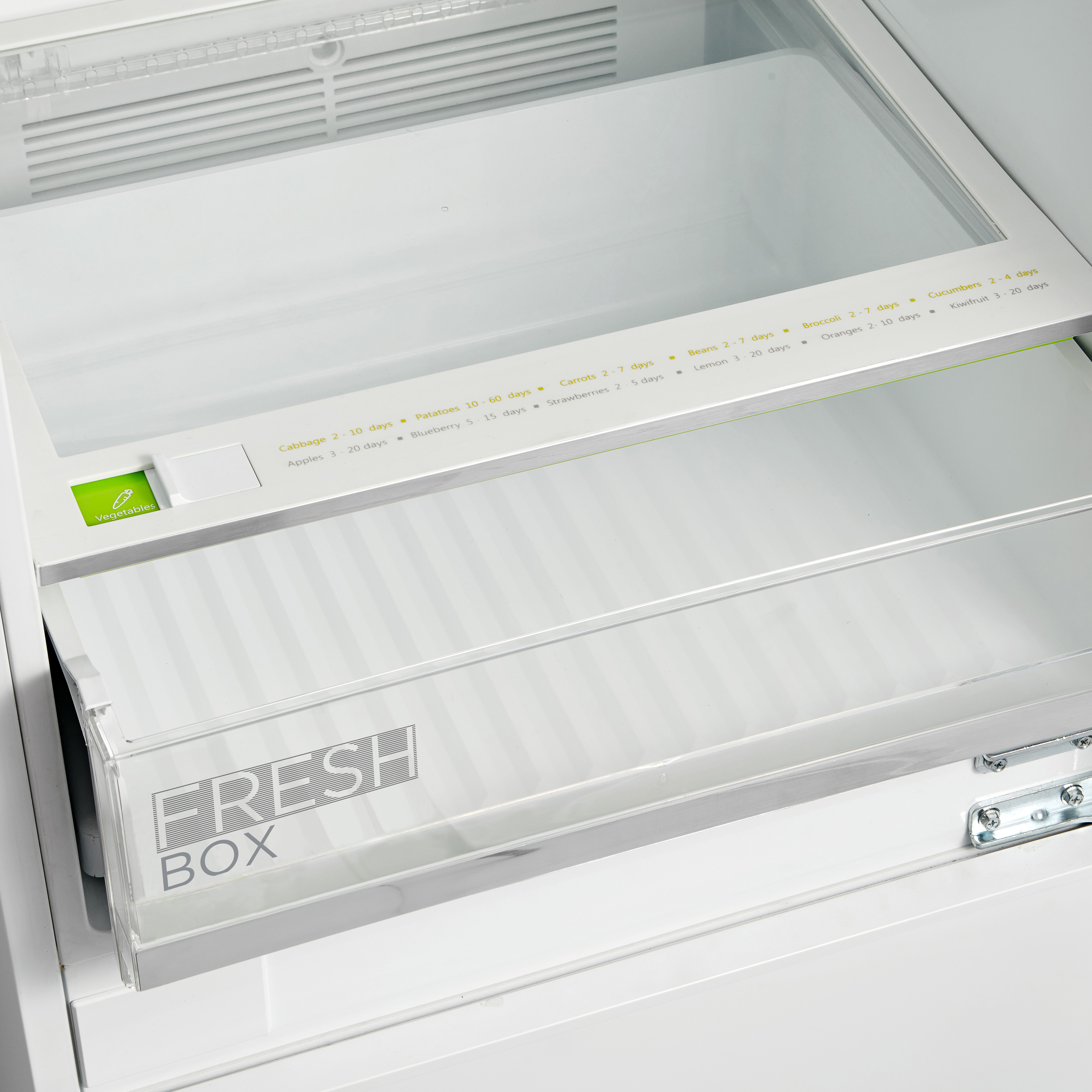 Dentro de una nevera, un cajón transparente para verduras con 'FRESH BOX' escrito, una balda superior e indicadores de caducidad.