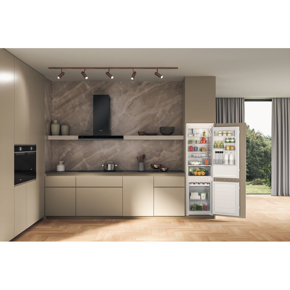 Cucina moderna con frigorifero aperto pieno di cibo, forno, armadi, pavimento in legno e finestra con tende.