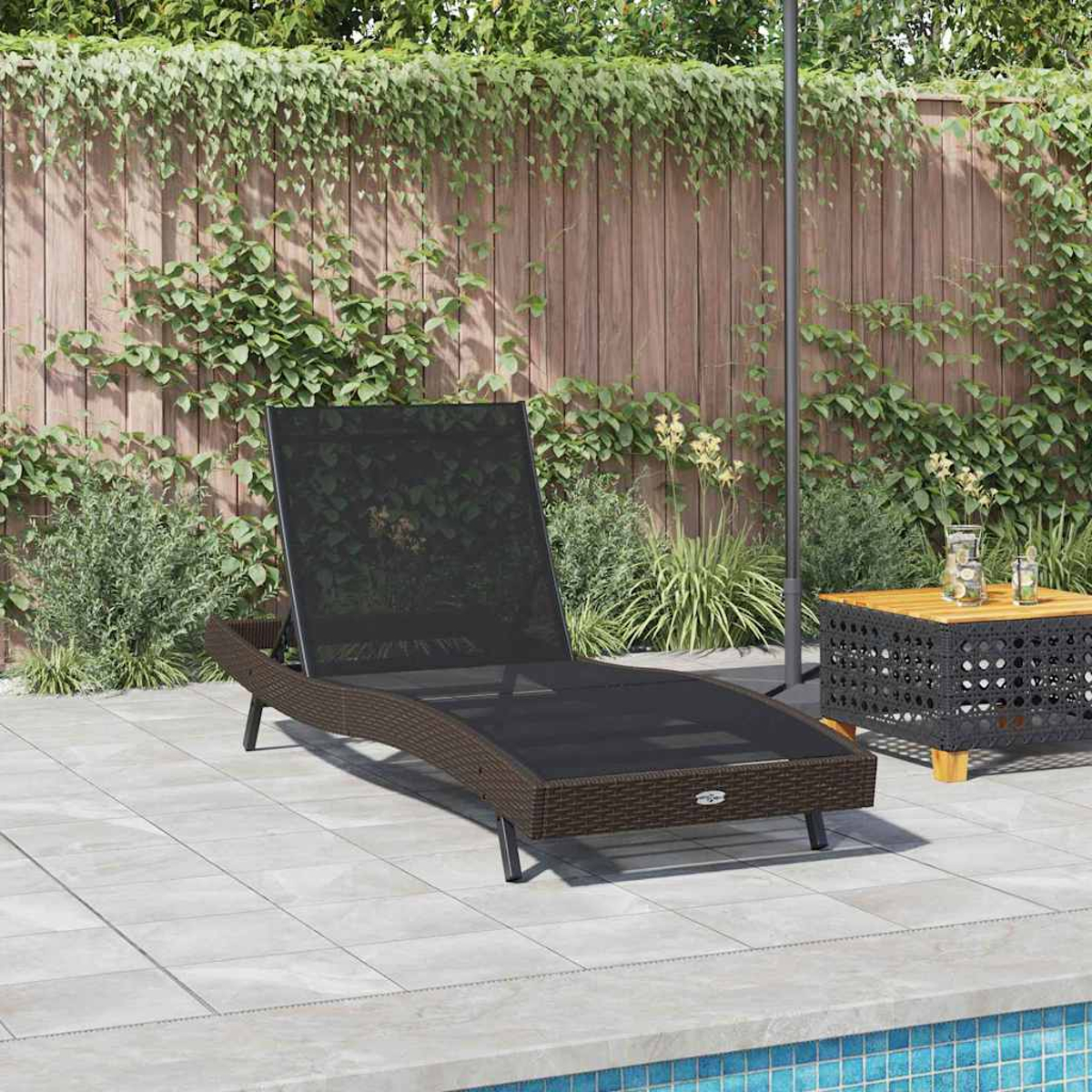 Außenszene mit braunem Rattan-Liegestuhl, kleinem Tisch, Pflanzen und Holzzaun.