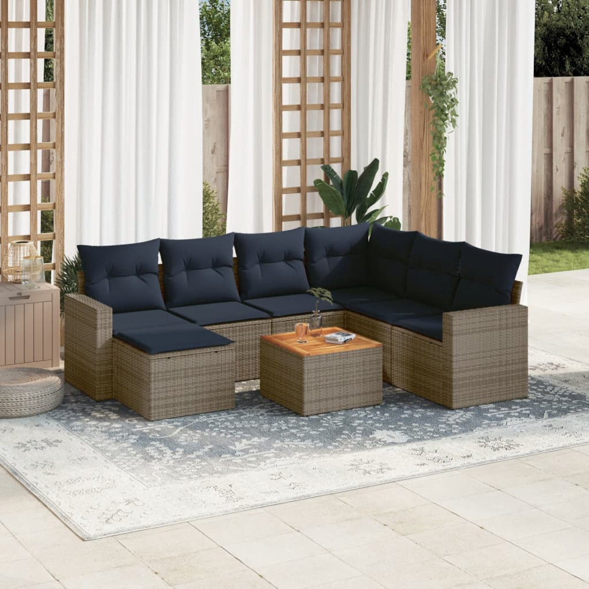 Garten-Sitzgruppe mit blauen Kissen und einem Holztisch auf einem gemusterten Teppich auf der Terrasse.