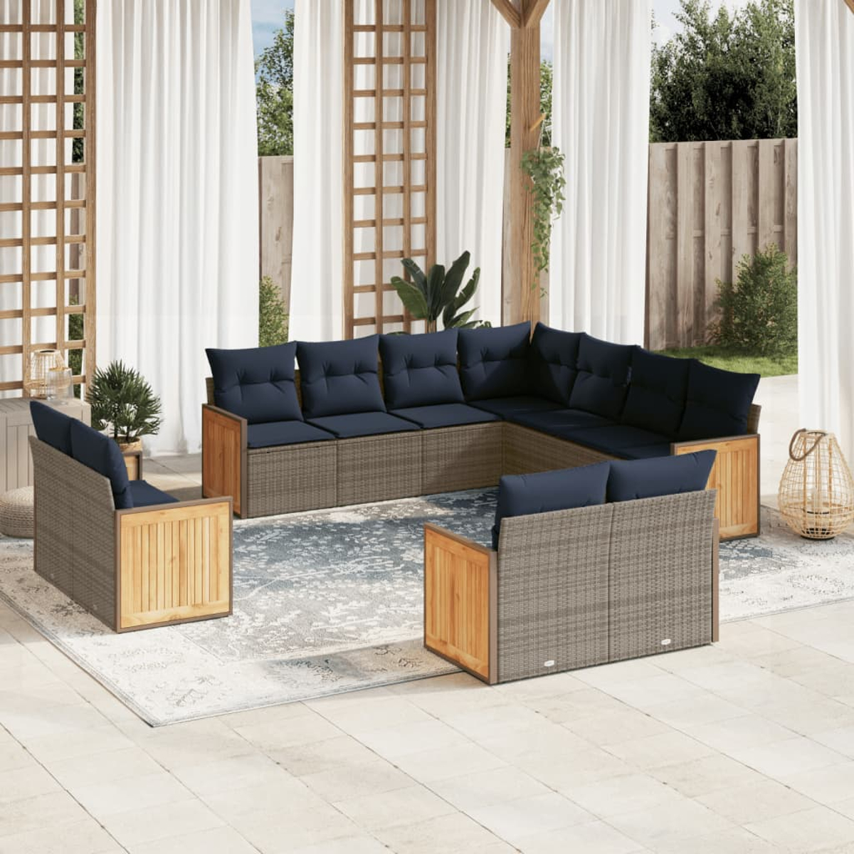 Outdoor-Sitzgruppe mit grauem Korbgeflecht und Holzakzenten. Marineblaue Kissen. Weiße Vorhänge und ein Teppich vervollständigen das Patio-Setting.