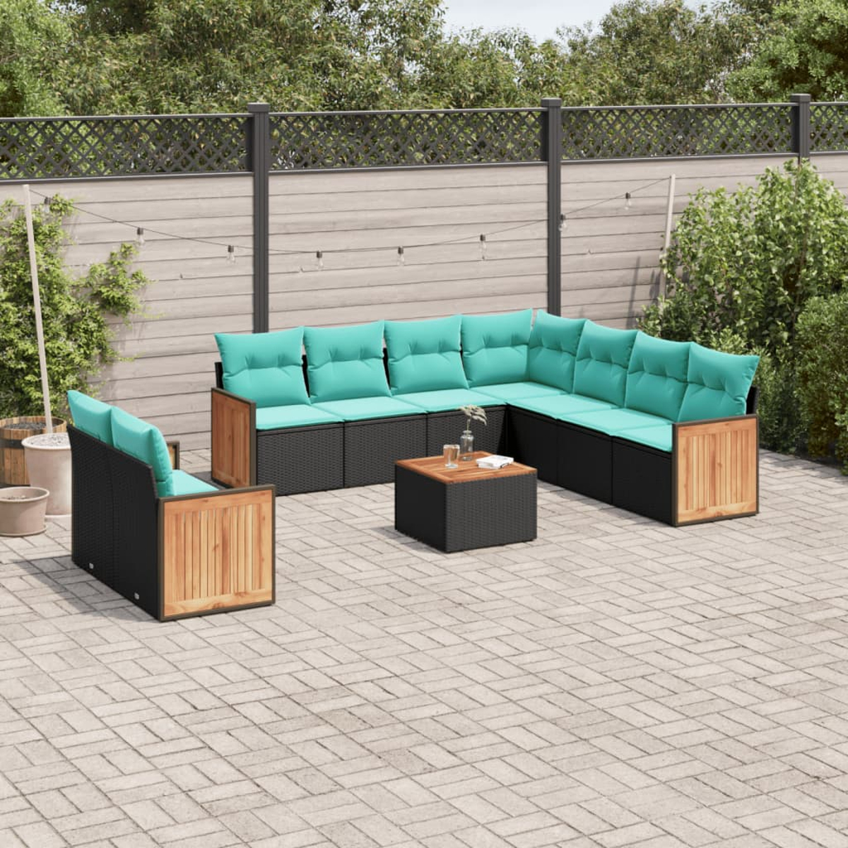 Juego de muebles de patio: base tejida negra con cojines turquesa y detalles de madera, en un patio pavimentado. Incluye una mesa.