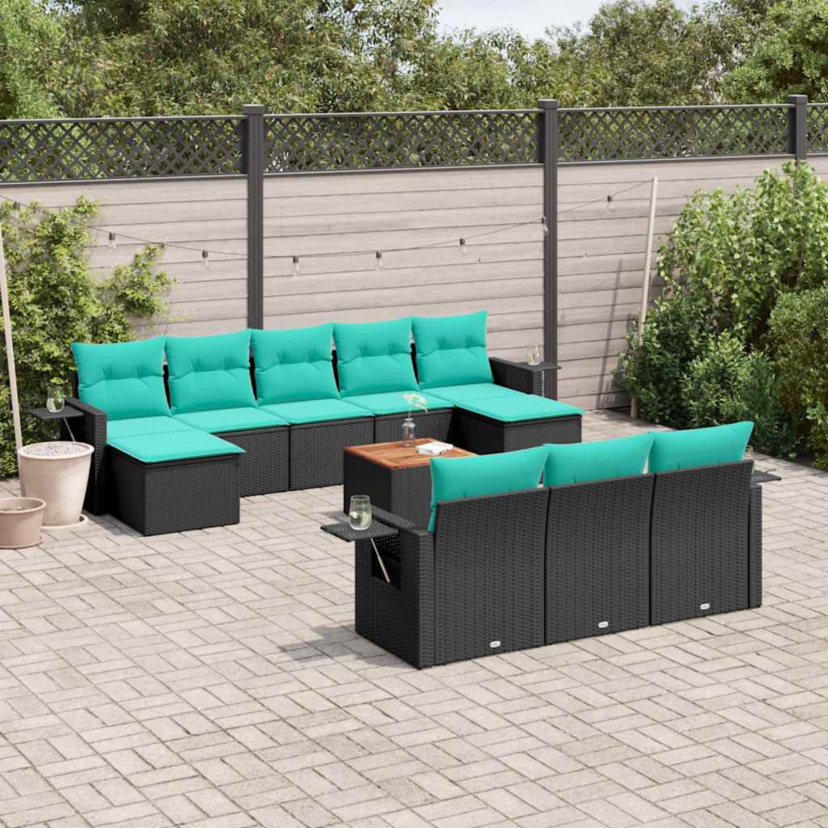 Gartenmöbel-Set mit türkisfarbenen Kissen und einem Holztisch. Gepflasterte Terrasse und Zaun im Hintergrund.
