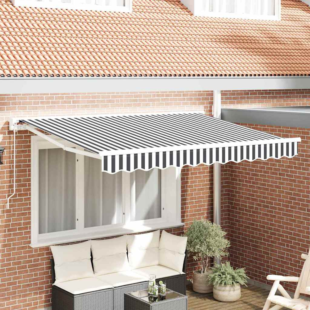 Un toldo a rayas cubre una ventana. Debajo hay un sofá, una mesa y plantas. El edificio tiene fachada de ladrillo y tejado de tejas.