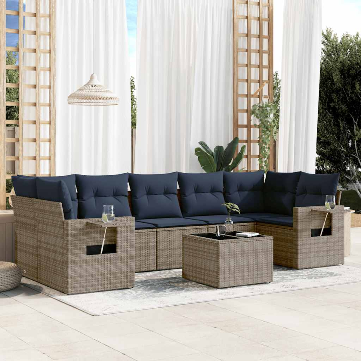 Garten-Terrassenset mit blauen Kissen, Rattangeflechtmöbeln und einem kleinen Tisch. Weiße Vorhänge und eine Hängelampe sind sichtbar.