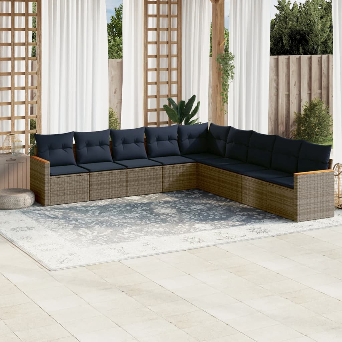 Ein Ecksofa im Freien mit marineblauen Kissen steht auf einer Terrasse. Weiße Vorhänge und ein Holzgitter sind im Hintergrund.