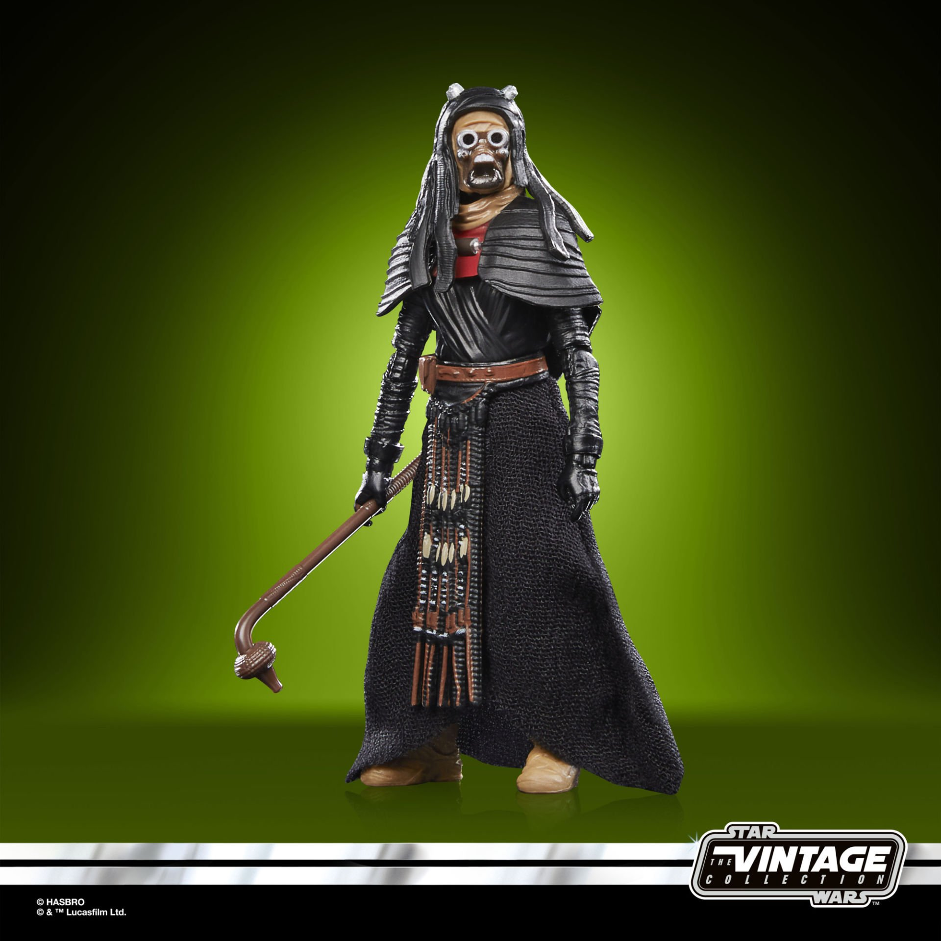 Figurka akcji Gwiezdnych Wojen. To wysoka postać w czarnej szacie, brązowym pasie i masce. Trzyma w ręku laskę.
