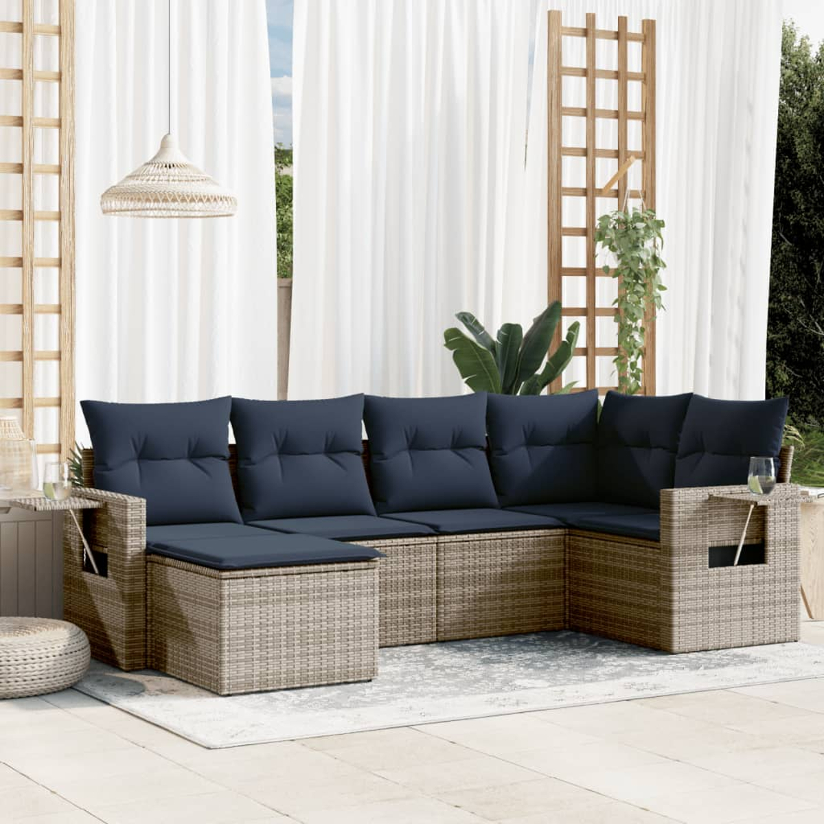 Outdoor-Ecksofa mit blauen Kissen, Korbgewebe, auf einer Terrasse. Weiße Vorhänge und Spalier im Hintergrund, hängende Pflanze.