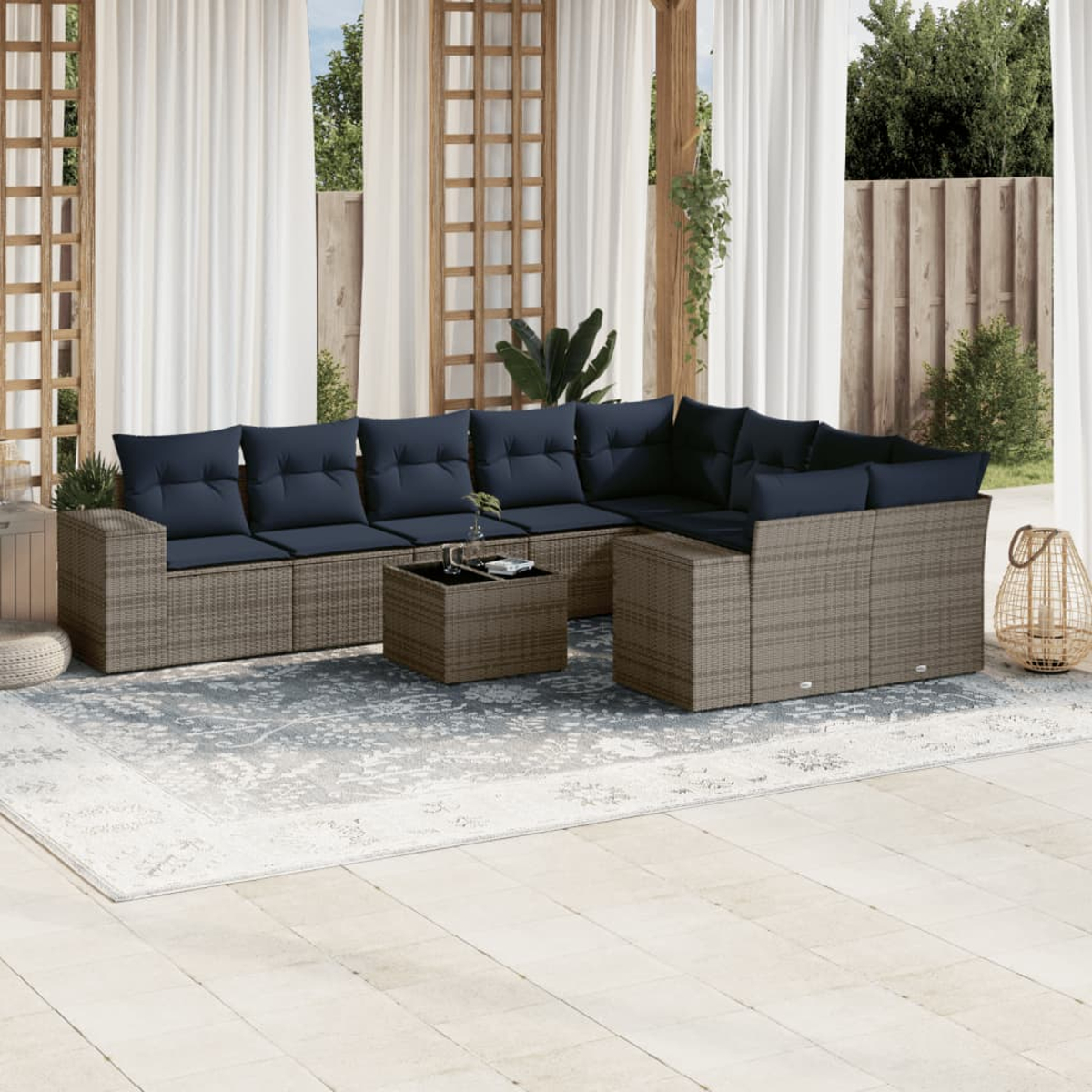 Outdoor-Ecksofa mit marineblauen Kissen, Couchtisch und Teppich. Hintergrund: Vorhänge, Holzgitter und Bäume.