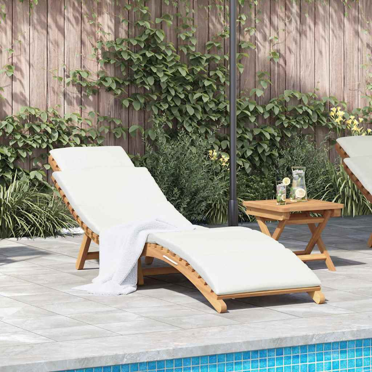 Eine weiß gepolsterte Liege mit Handtuch, neben einem kleinen Tisch mit Getränken, in der Nähe eines Pools. Dahinter ein Holzzaun mit Grün.