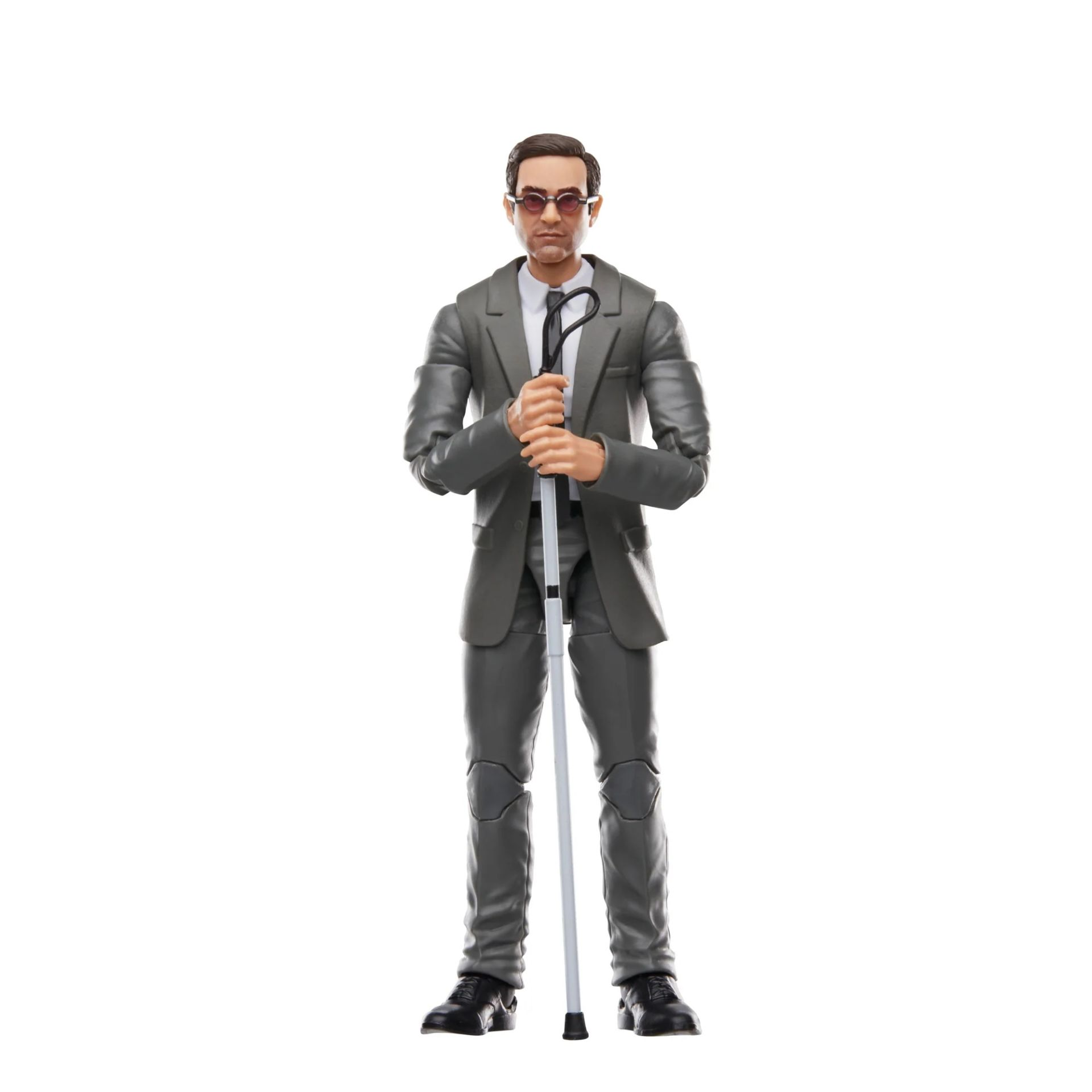Un hombre con traje gris y gafas de sol está de pie con un bastón blanco. Sostiene el bastón delante de él. Fondo blanco.