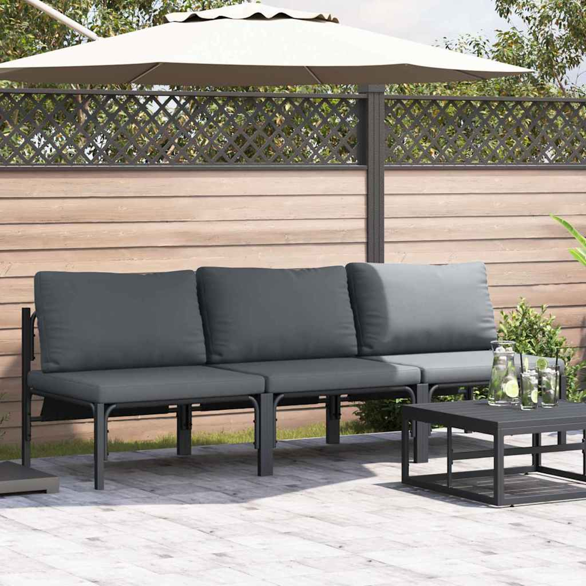 Graues Outdoor-Sofa mit Kissen, kleiner Tisch, weißer Sonnenschirm und Holzzaun im Hintergrund.