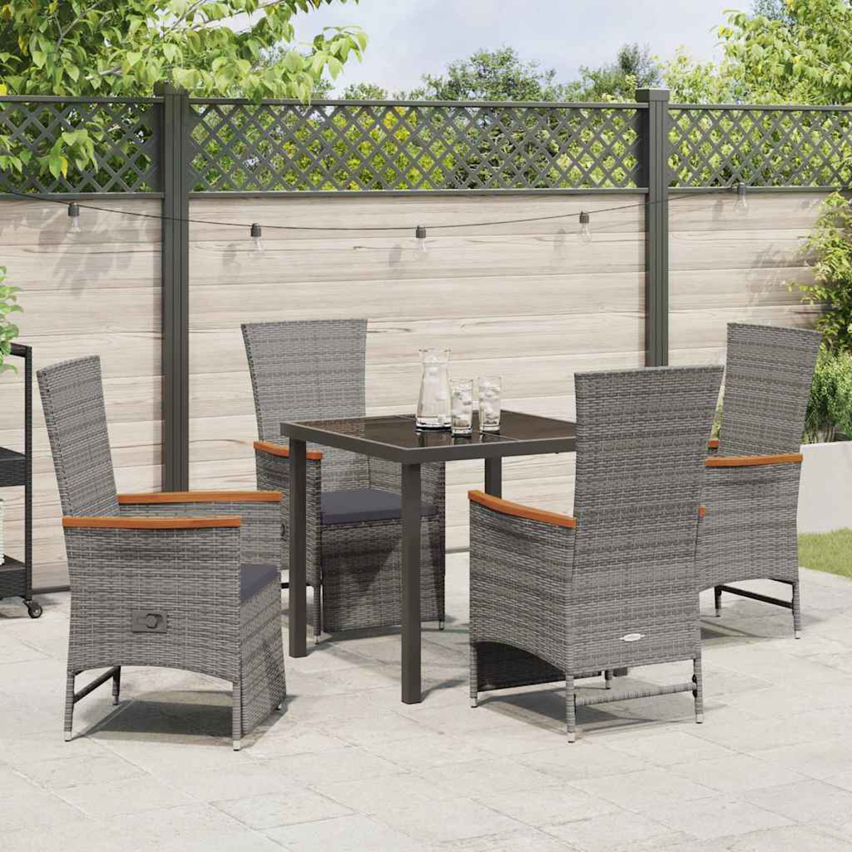 Un set da pranzo grigio da esterno con un tavolo quadrato e quattro sedie è su un patio. Una recinzione e vegetazione sono sullo sfondo.
