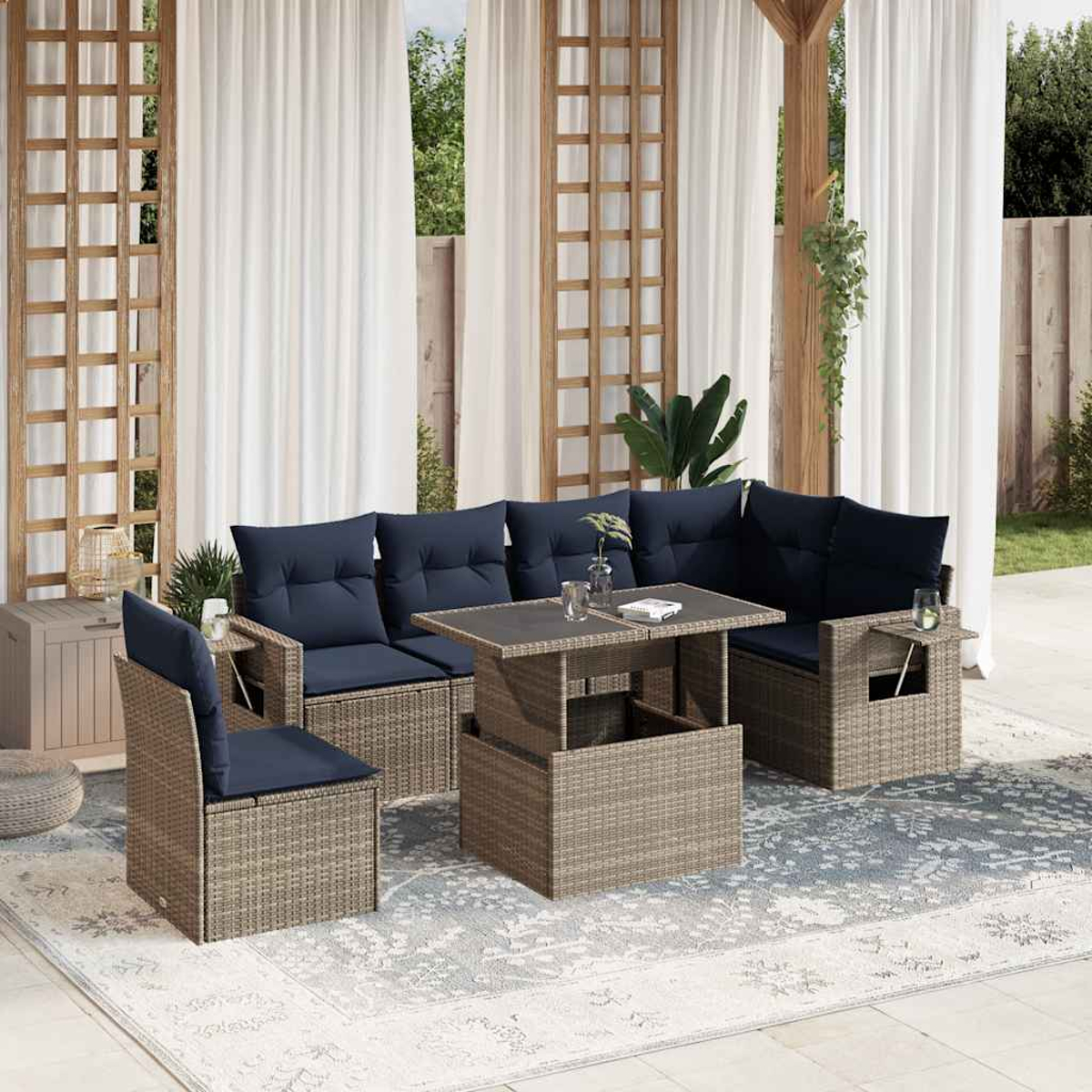 Gartenmöbel: Rattan-Sofa und -Stühle mit marineblauen Kissen, ein Couchtisch und weiße Vorhänge im Hintergrund.