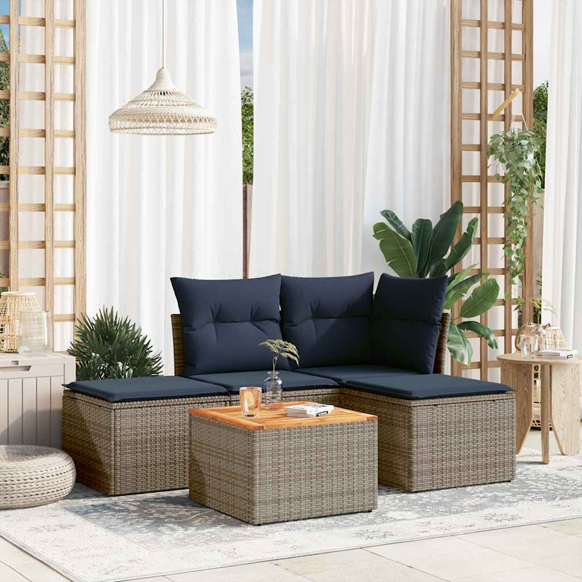 Outdoor-Sitzgruppe mit marineblauen Kissen, einem Holztisch und weißen Vorhängen im Hintergrund, mit Pflanzen.