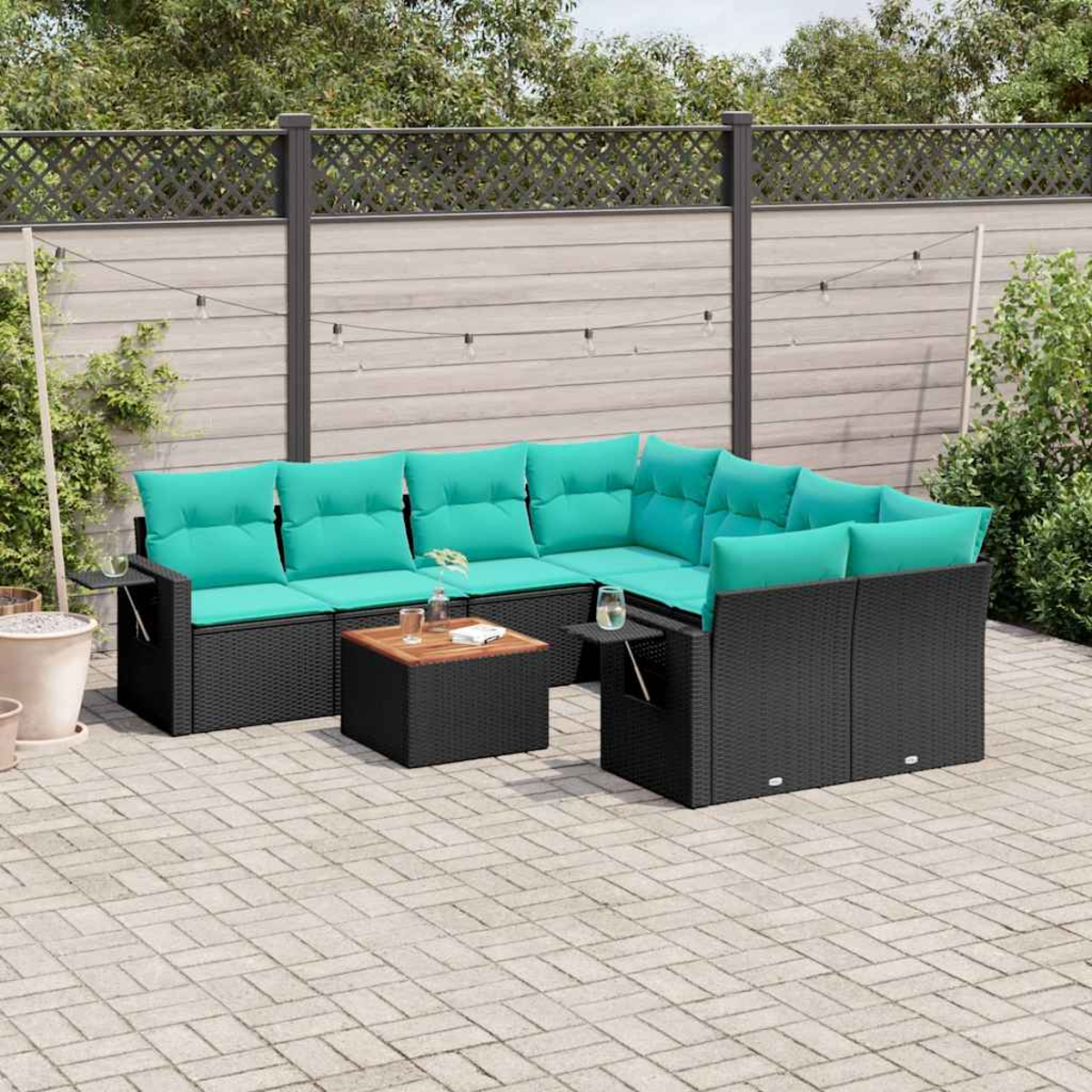 Garten-Sitzgruppe mit schwarzen Korbflechtrahmen und türkisfarbenen Kissen. Ein Holztisch und Getränke befinden sich auf einer Terrasse. Hinten ist ein Zaun.