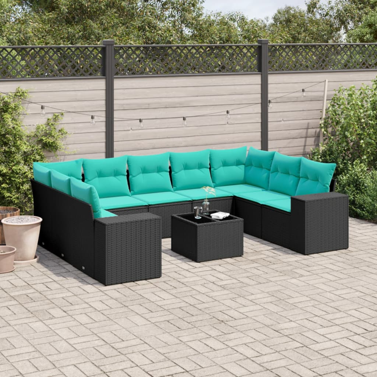 Outdoor-Ecksofa mit türkisfarbenen Kissen und einem schwarzen Korbgeweberahmen auf einer Ziegelterrasse. Vorne steht ein kleiner Tisch.