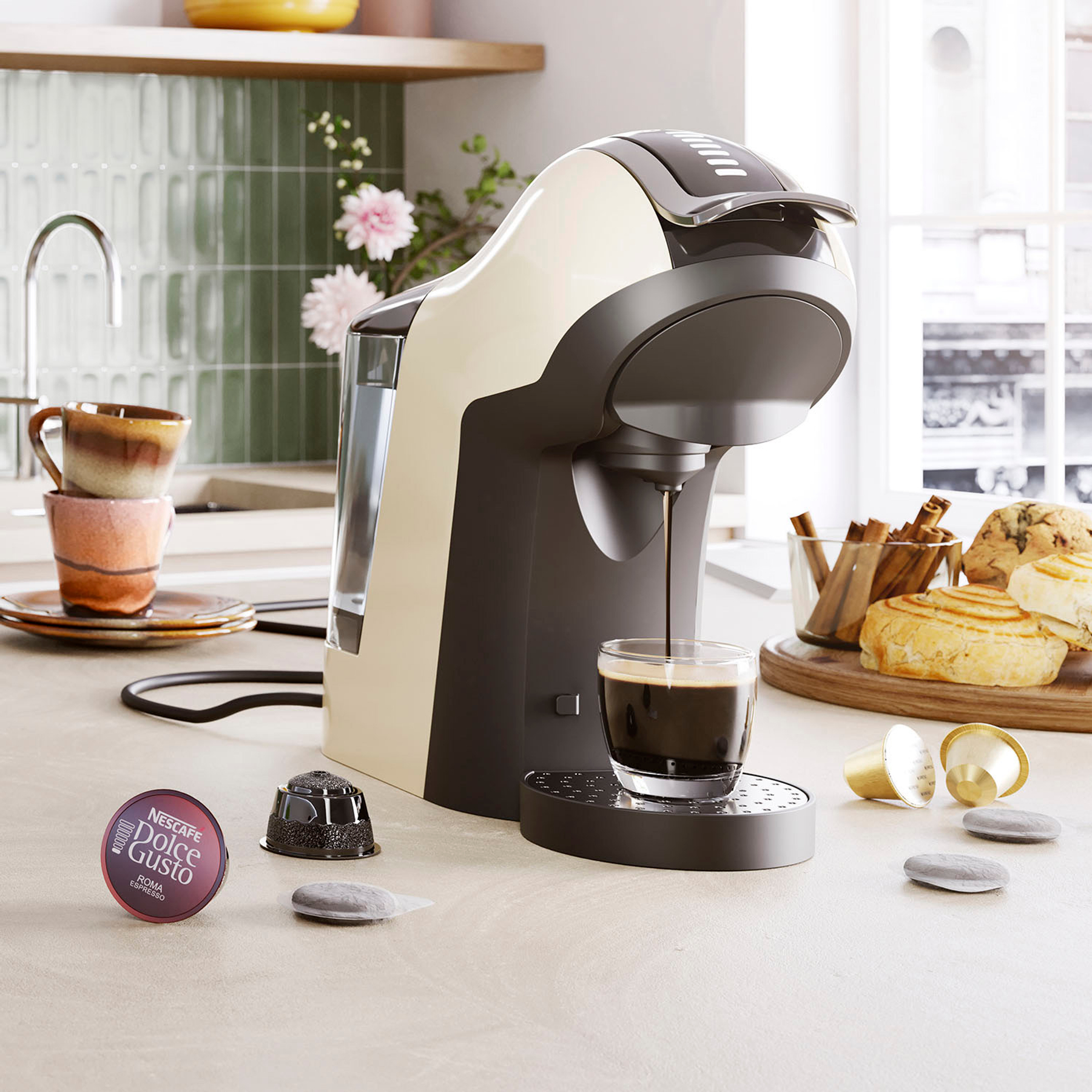 Ekspres do kawy dozujący kawę do szklanki, z kapsułkami i ciastkami na blacie.