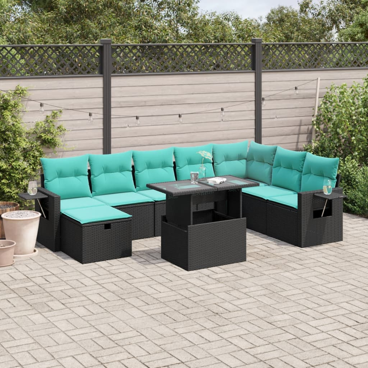 Outdoor-Sektion aus schwarzem Korbgeflecht mit türkisfarbenen Kissen und einem passenden Couchtisch auf einer gepflasterten Terrasse.