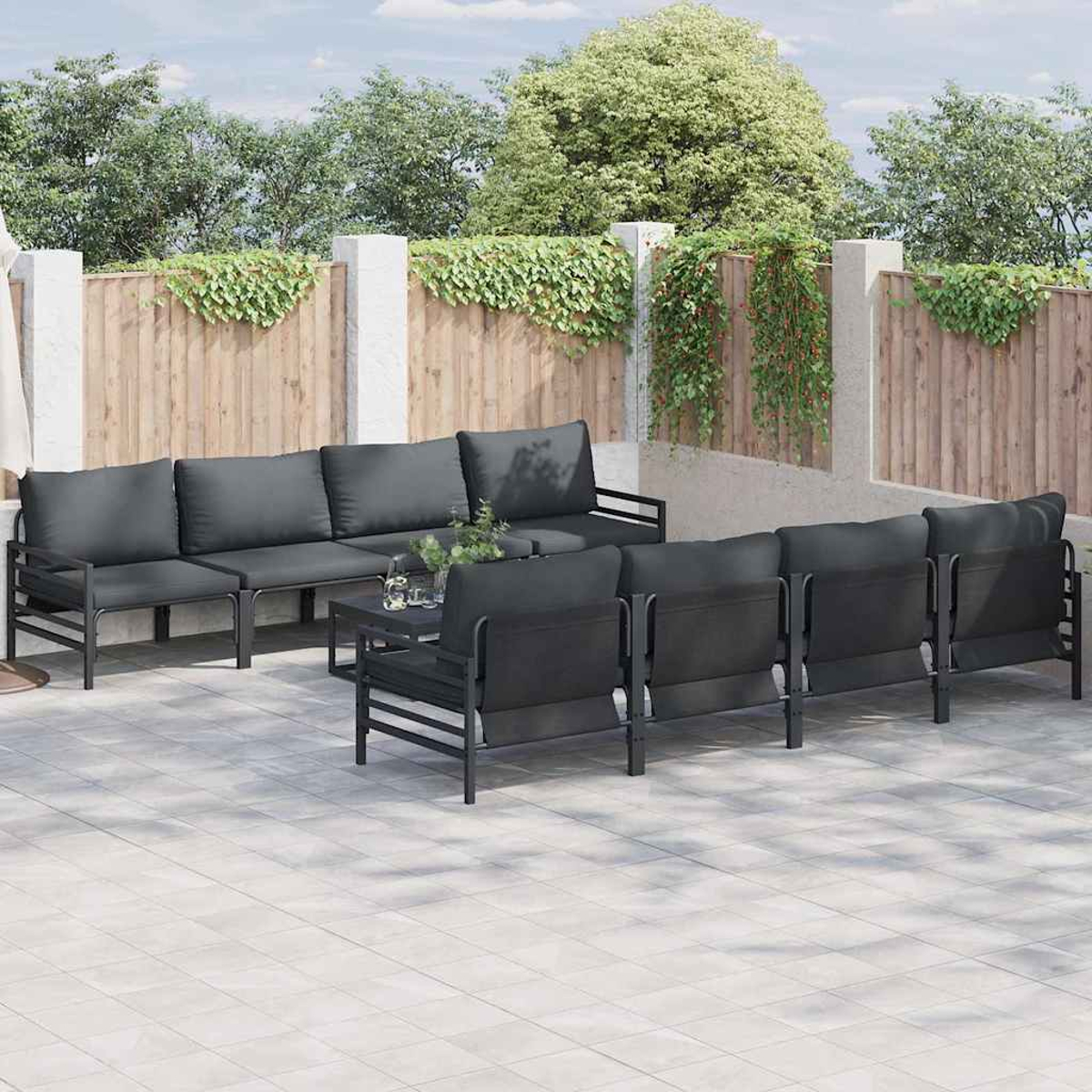 Outdoor-Terrassenset mit dunkelgrauen Kissen und schwarzen Rahmen. Auf gefliestem Patio. Holzzaun im Hintergrund mit grünen Ranken.