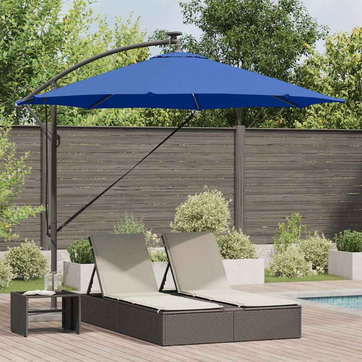 Scena all'aperto con ombrellone blu, due sedie a sdraio, tavolino, terrazza in legno e recinzione.