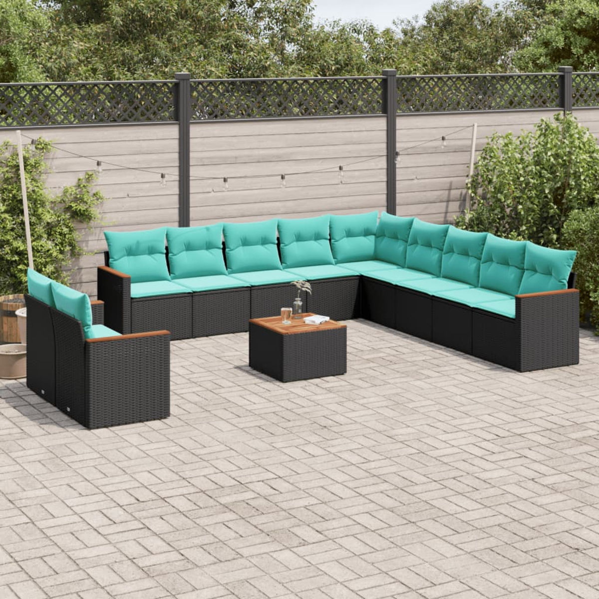 Terrassen-Set mit tealfarbenen Kissen. Enthält ein Ecksofa, einen Stuhl und einen quadratischen Couchtisch auf einer Ziegelterrasse.