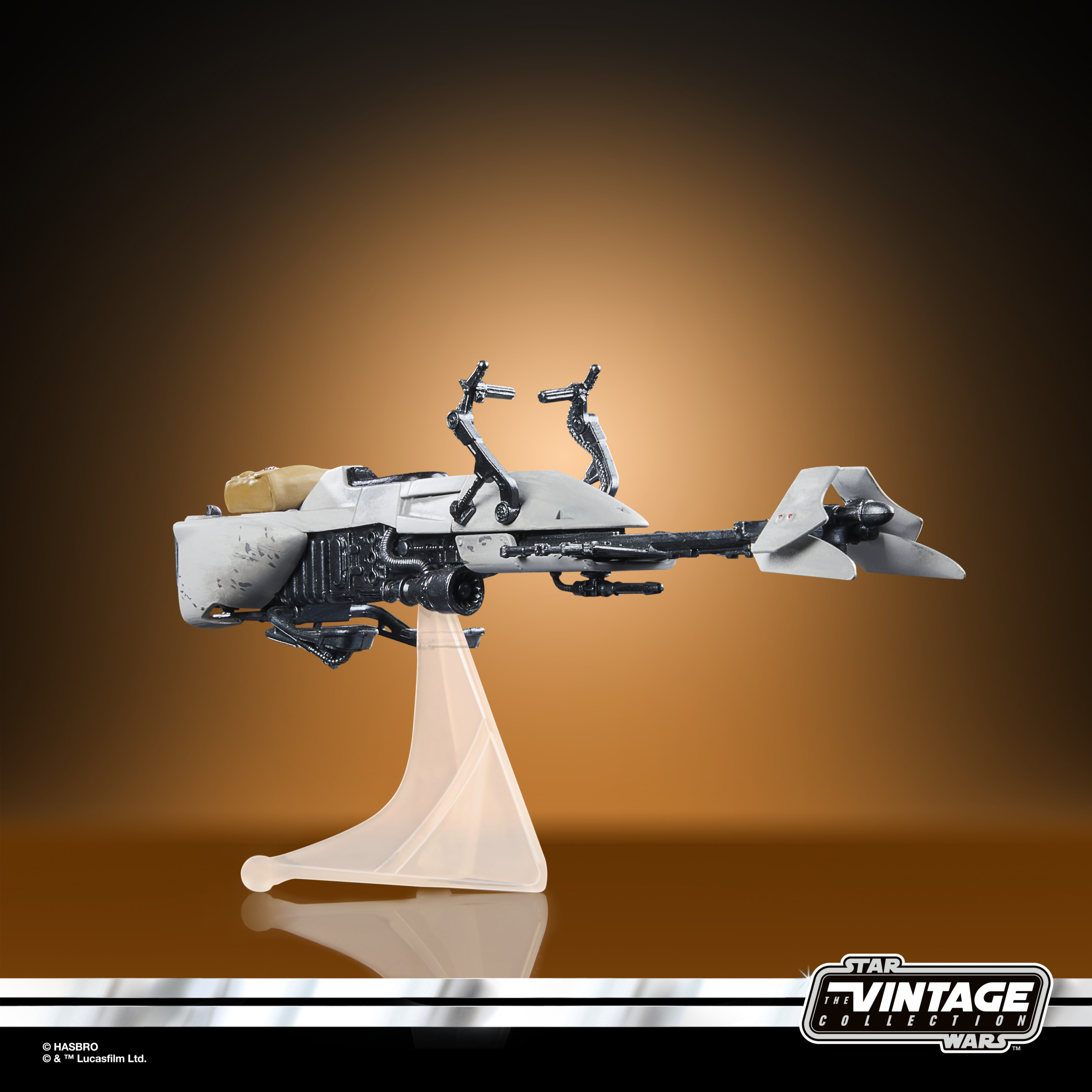 Beyaz bir Speeder Bike'ın bulunduğu bir Star Wars oyuncağı, kahverengi gradyan bir arka plan üzerinde şeffaf bir standdadır.
