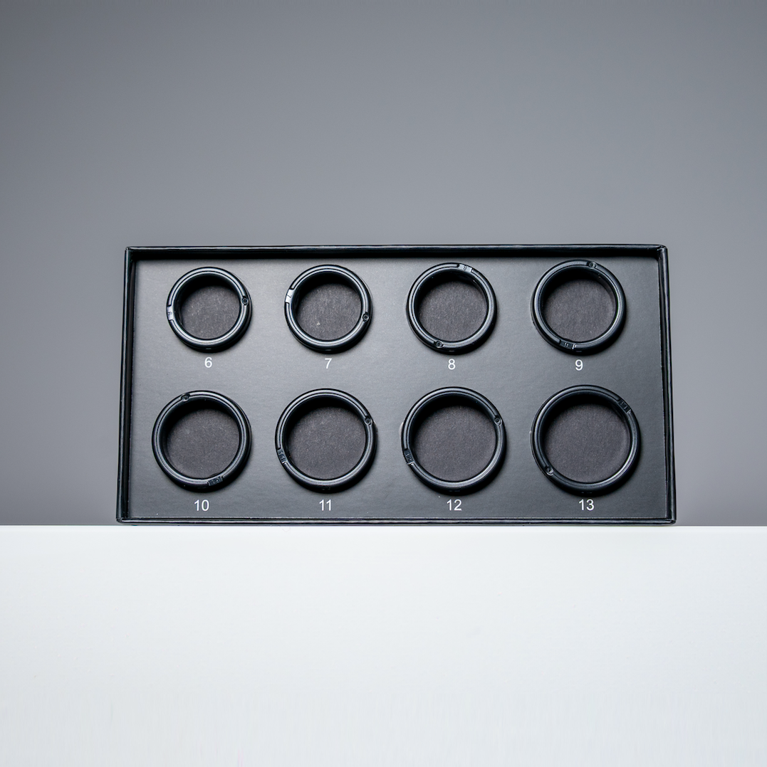 Eine schwarze Box mit acht kreisförmigen Öffnungen. Jede Öffnung hat eine Nummer von 6 bis 13. Der Hintergrund ist grau und weiß.