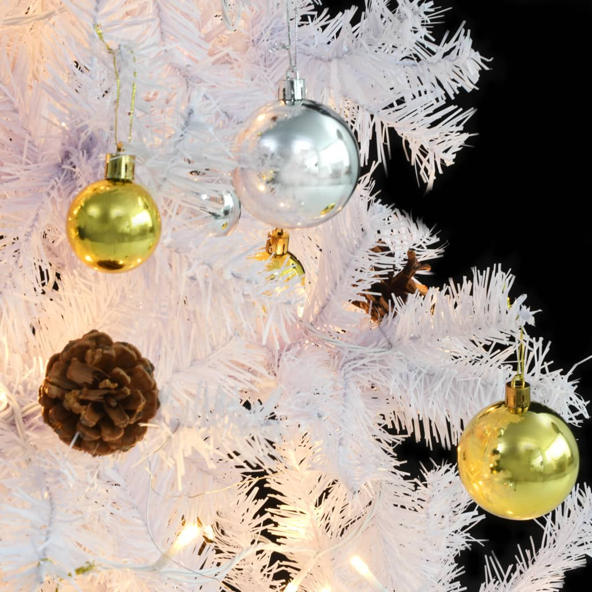 Weißer Weihnachtsbaum mit Ornamenten. Gold- und Silberkugeln, eine Tannenzapfen und Lichter auf schwarzem Hintergrund.