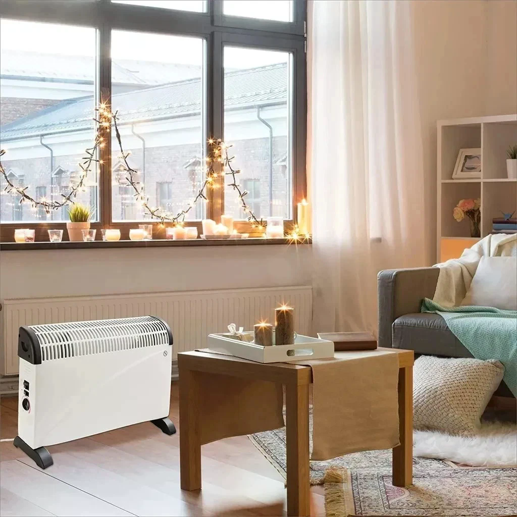 Een woonkamer met een witte kachel, een tafel met kaarsen, een raam met lichtjes en kaarsen en een bank met een deken.