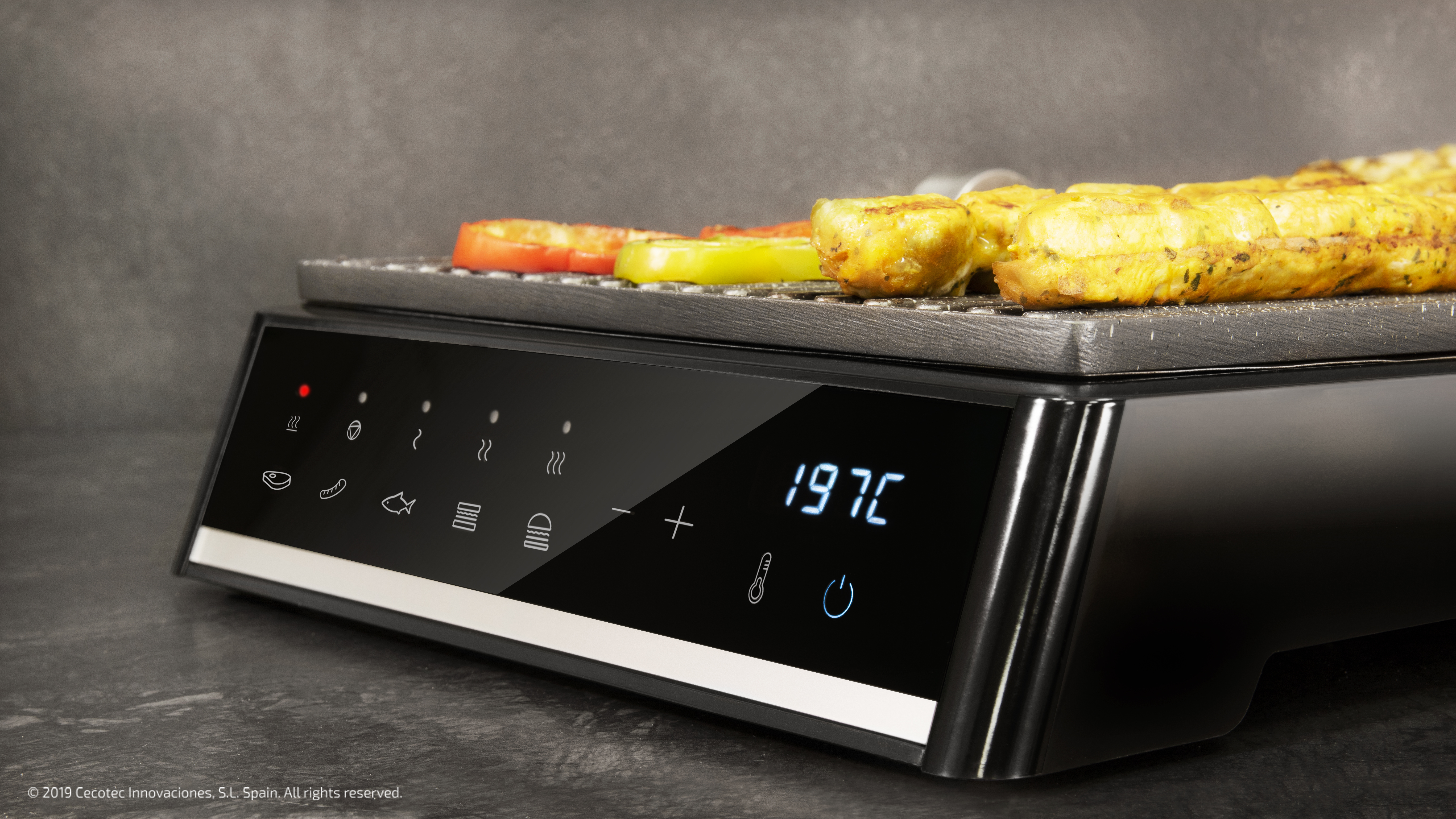 Czarny grill elektryczny z warzywami i grillowanym jedzeniem. Wyświetlacz pokazuje 197C. Tło jest ciemne.