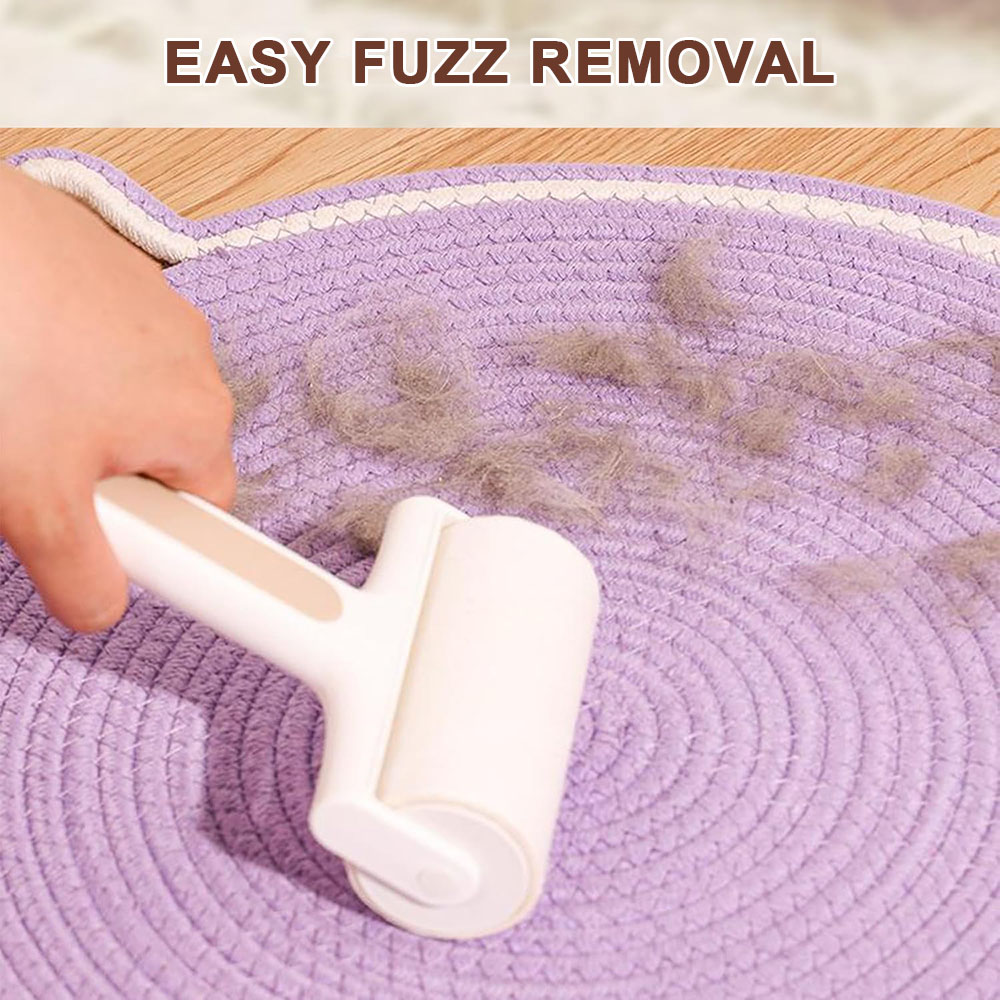 Eine Hand benutzt eine weiße Fusselrolle auf einer lila gewebten Matte, um graue Fusseln zu entfernen. Oben steht 'EASY FUZZ REMOVAL'.