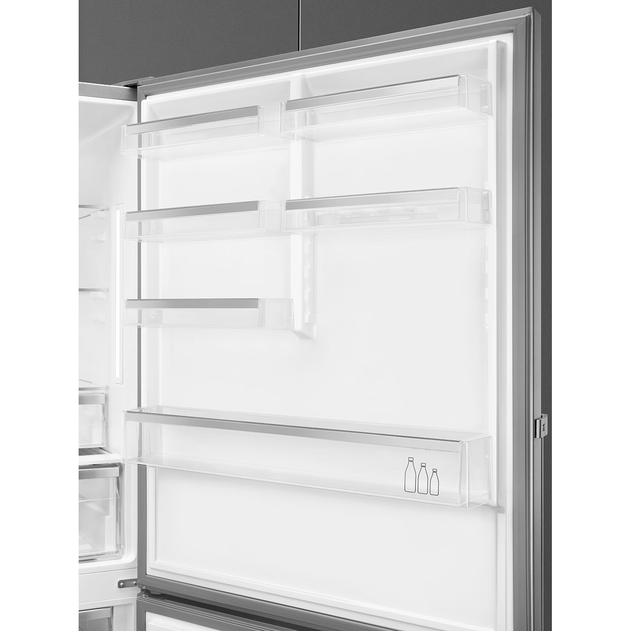 Interno di frigorifero aperto e vuoto, con ripiani trasparenti e grafica di bottiglie. La porta socchiusa rivela elementi bianchi e grigi.