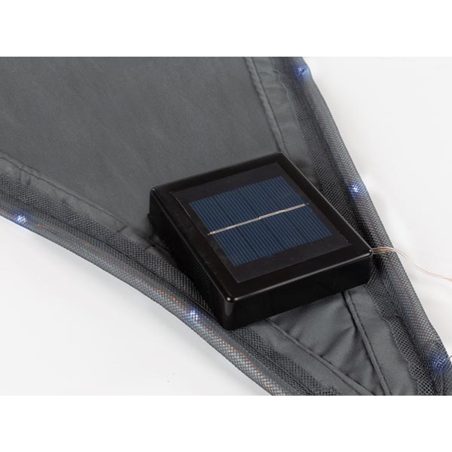 Un pannello solare nero su un tessuto grigio. Il tessuto ha un bordo in rete con piccole luci blu. Sfondo bianco.