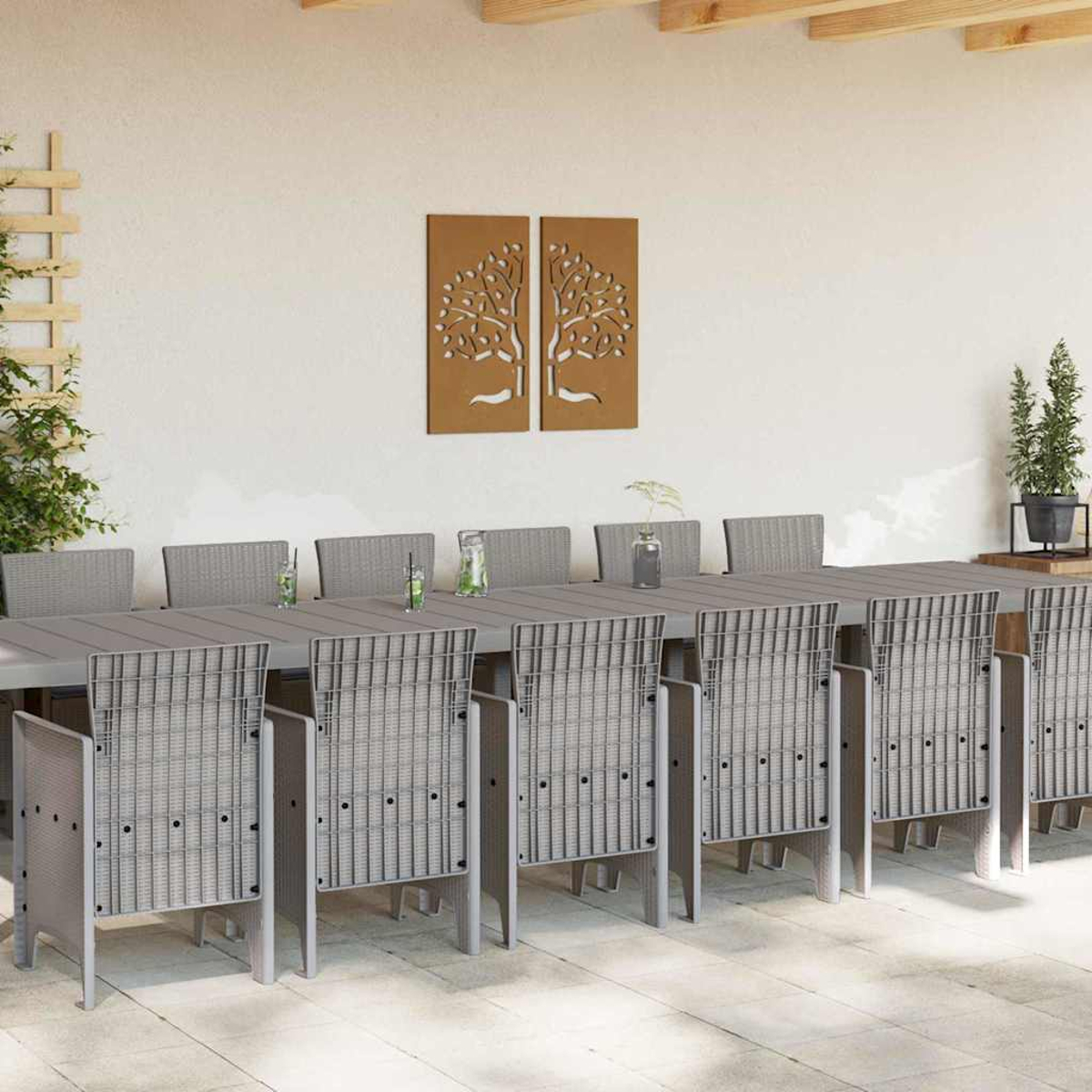 Essgruppe im Freien mit langem Tisch und Stühlen. Braune Baumkunst an der Wand. Pflanzen und Getränke stehen auf dem Tisch.