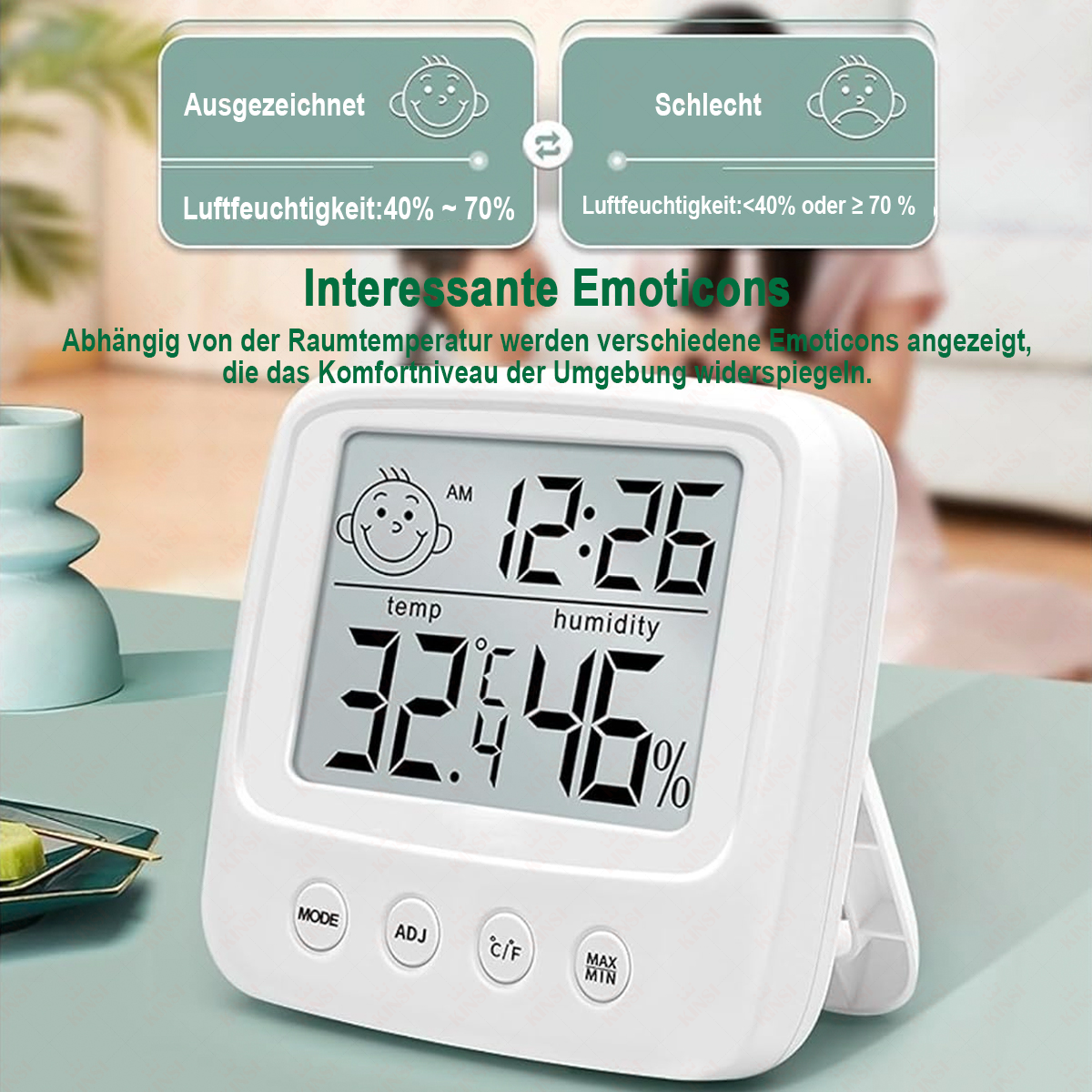 Ein weißes Digitalthermometer zeigt Zeit, Temperatur und Luftfeuchtigkeit an. Es hat ein Smiley-Symbol und Text, der die Luftfeuchtigkeit angibt.