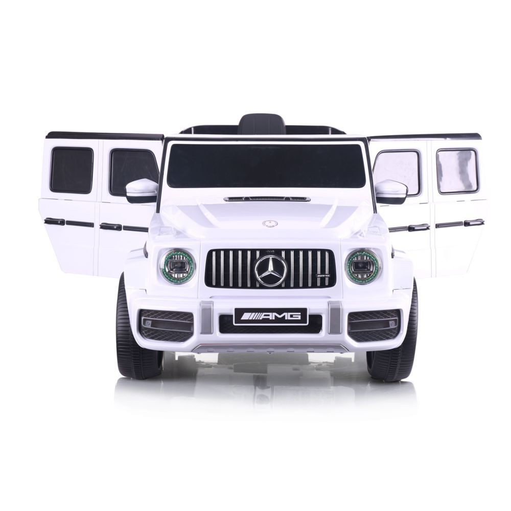 Ein weißer Spielzeug-Mercedes-Benz G-Wagon mit offenen Türen steht auf einer weißen Oberfläche. Das AMG-Logo ist sichtbar.