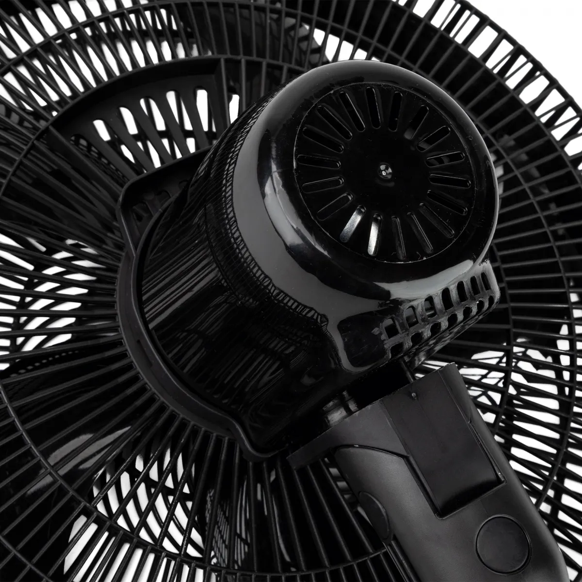 Primer plano de un ventilador eléctrico negro. Se ven las aspas del ventilador, así como la carcasa del motor y el soporte. Fondo blanco.